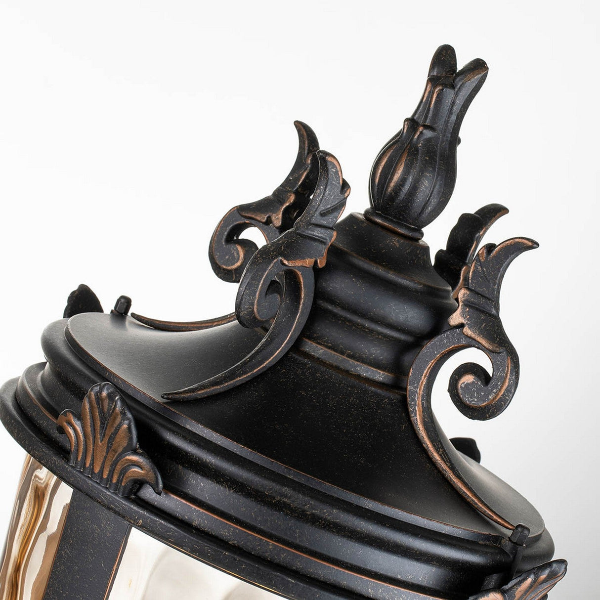 Close-up of the Baltimore 1 Light Large Pedestal Lantern, showcasing ornate scrollwork and floral patterns. This pedestal lantern, finished in weathered bronze, exudes a vintage look with its pointed top and slightly aged finish, set against a plain white background.