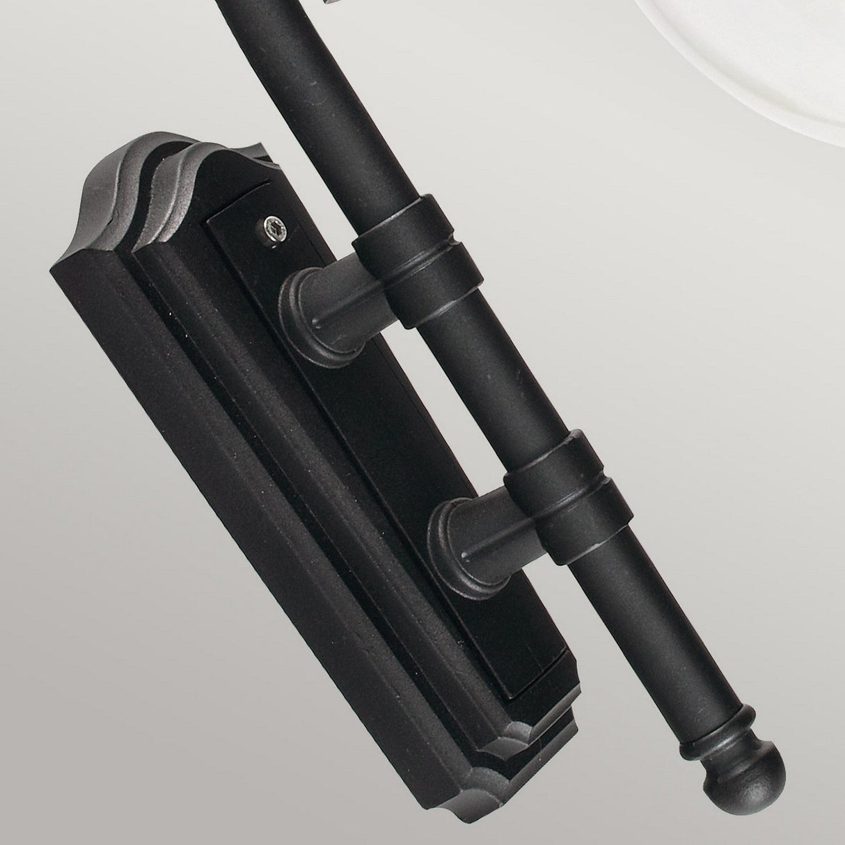 Close-up of the Como Outdoor 1 Light Wall Lantern in black, displaying a sleek and modern design. The fixture, reminiscent of a black powder-coated lantern, features a cylindrical arm and a rectangular base with decorative edges.