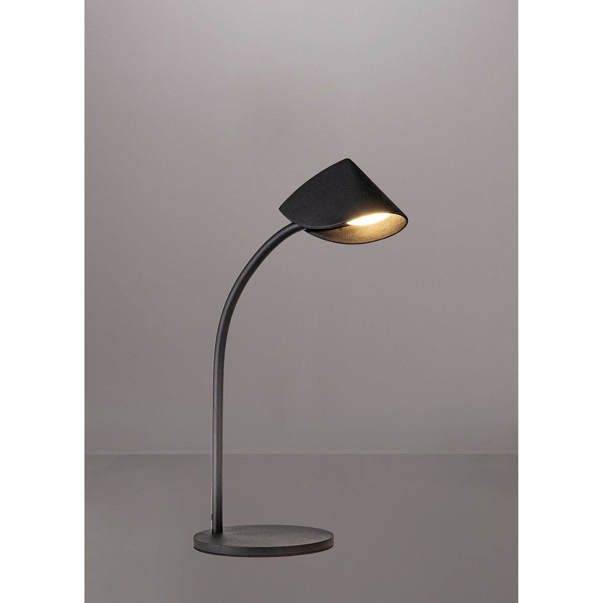 Capuccina Small LED table lamp with folded cone shade in matt black on a curved stem and circular base, illuminated against a light grey background.
