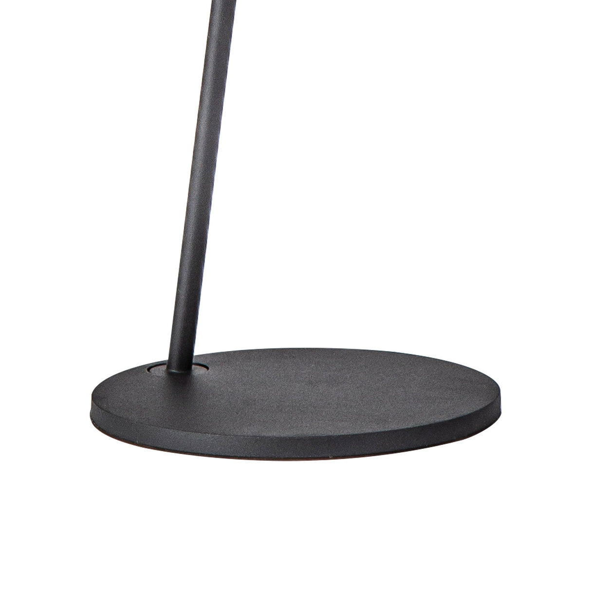 A close-up of the Capuccina LED Floor Lamp 8.5W 3000K in Black shows its round, flat base and slender vertical pole against a white background.
