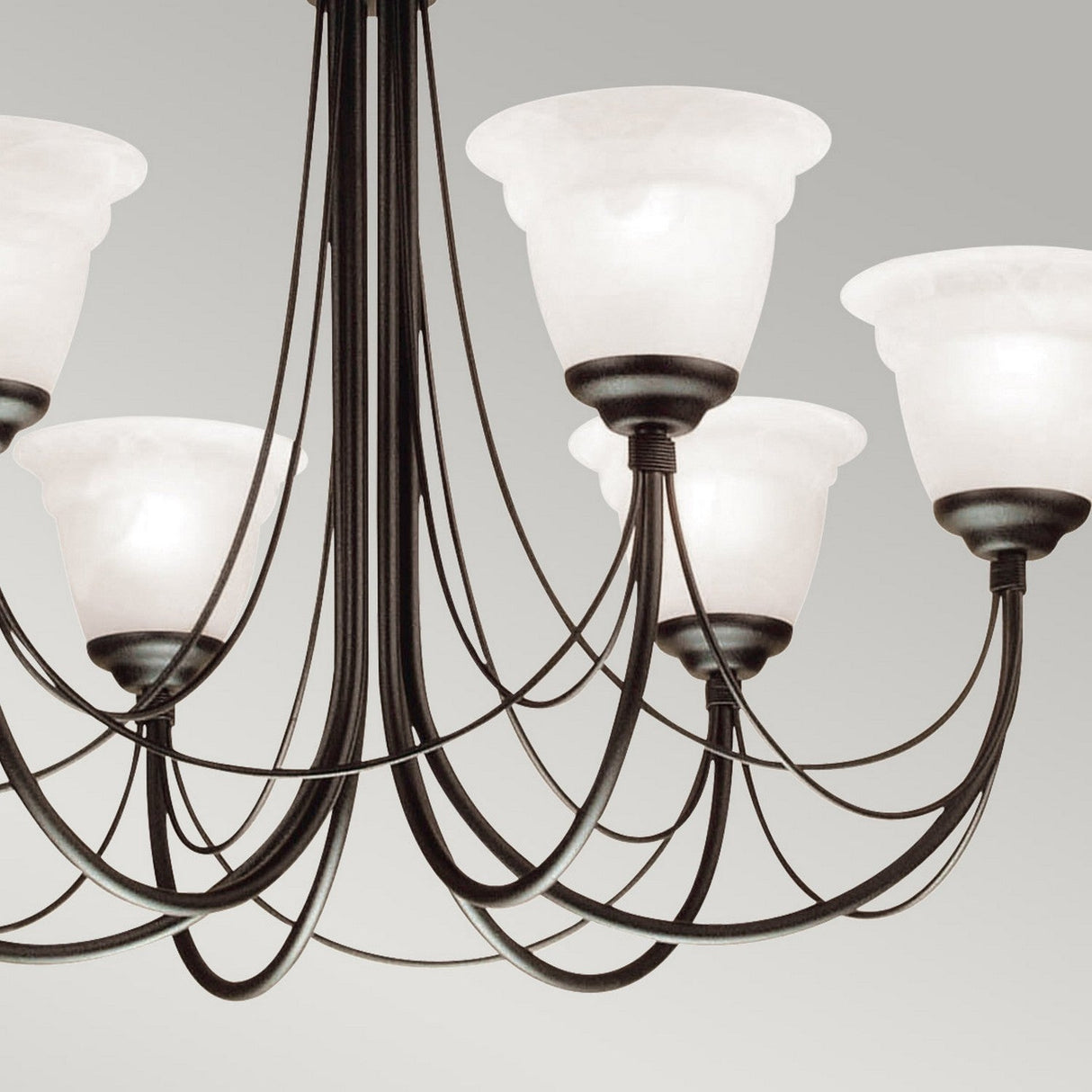 A close-up of the Carisbrooke 6 Light Chandelier - Black highlights its dark metal frame and multiple curved arms, each supporting a frosted white glass lampshade. The plain light gray backdrop enriches its vintage aesthetic with a touch of Gothic elegance.