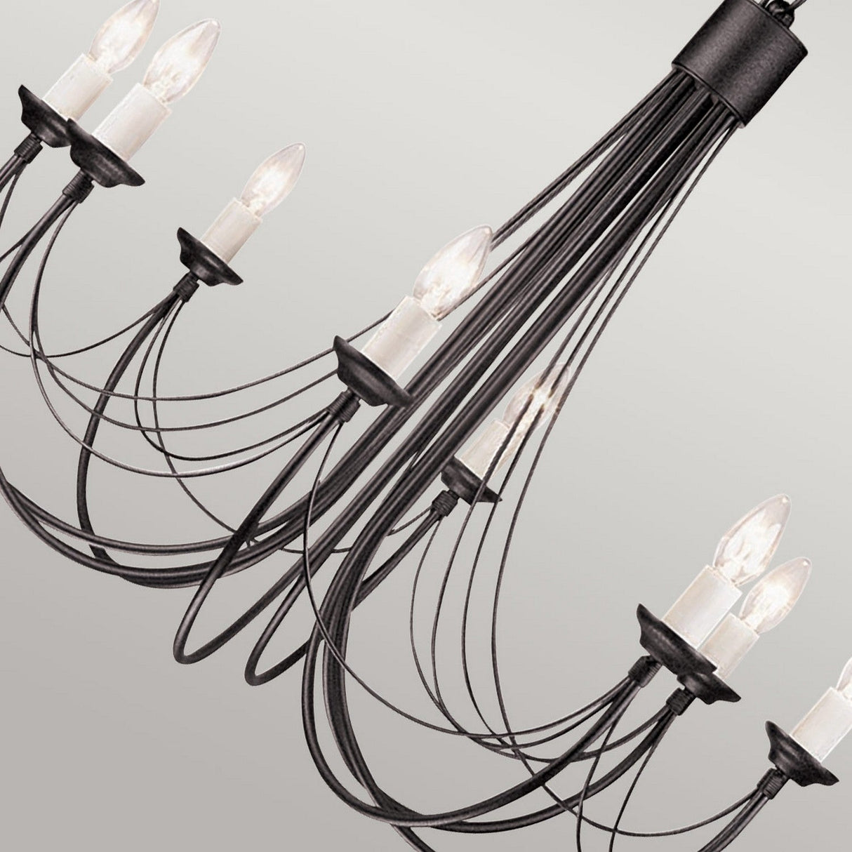The Carisbrooke 8 Light Chandelier - Black features a contemporary design with several black metal arms, each supporting a candle-shaped bulb. When placed against a simple background, its refined curves and flowing lines exude a vintage charm reminiscent of Gothic-inspired sophistication.
