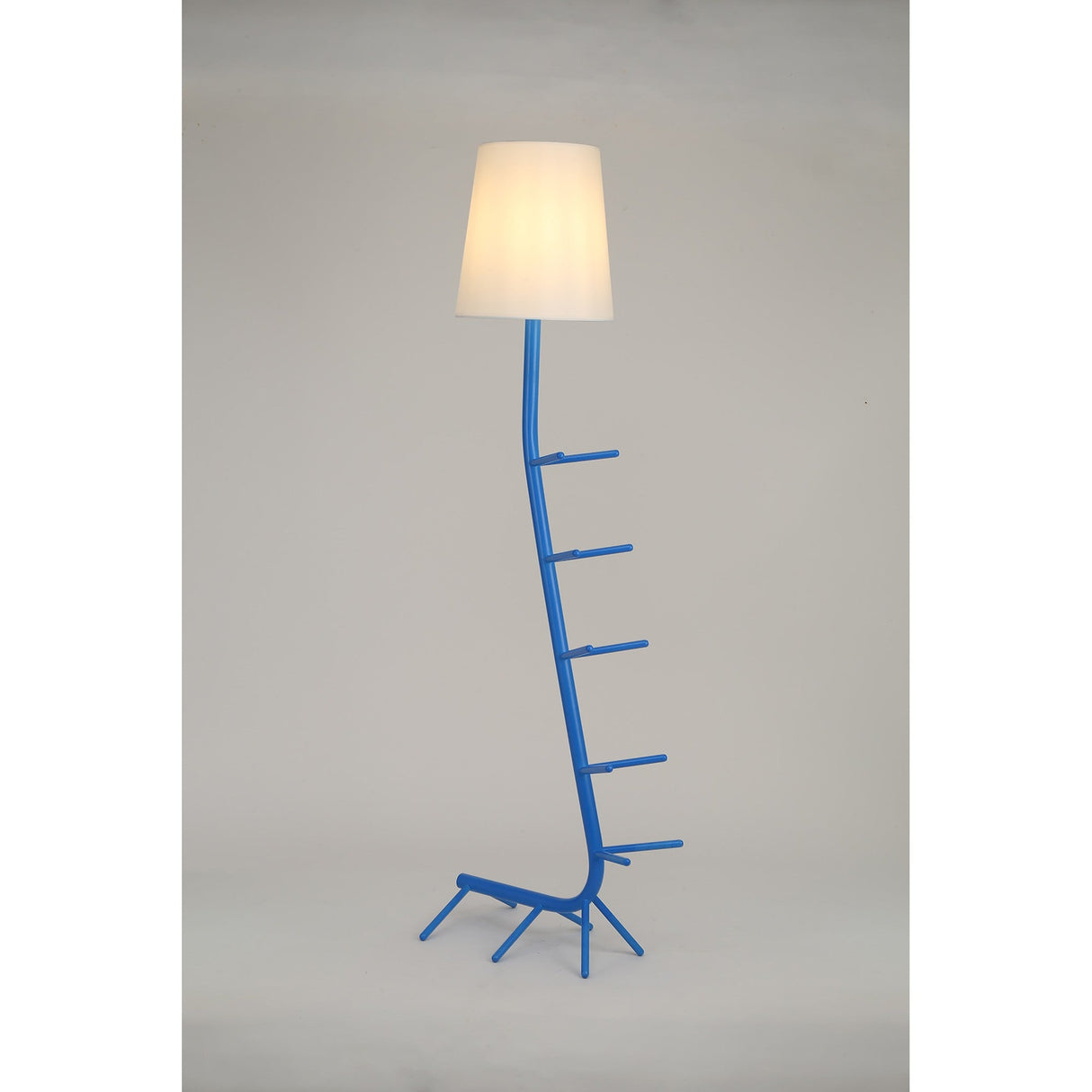 The Centipede 1 Light Floor Lamp in blue, featuring horizontal branch-like arms and a white shade, brings striking modern style to interiors. Set against a light gray backdrop, its bold design makes a contemporary statement.