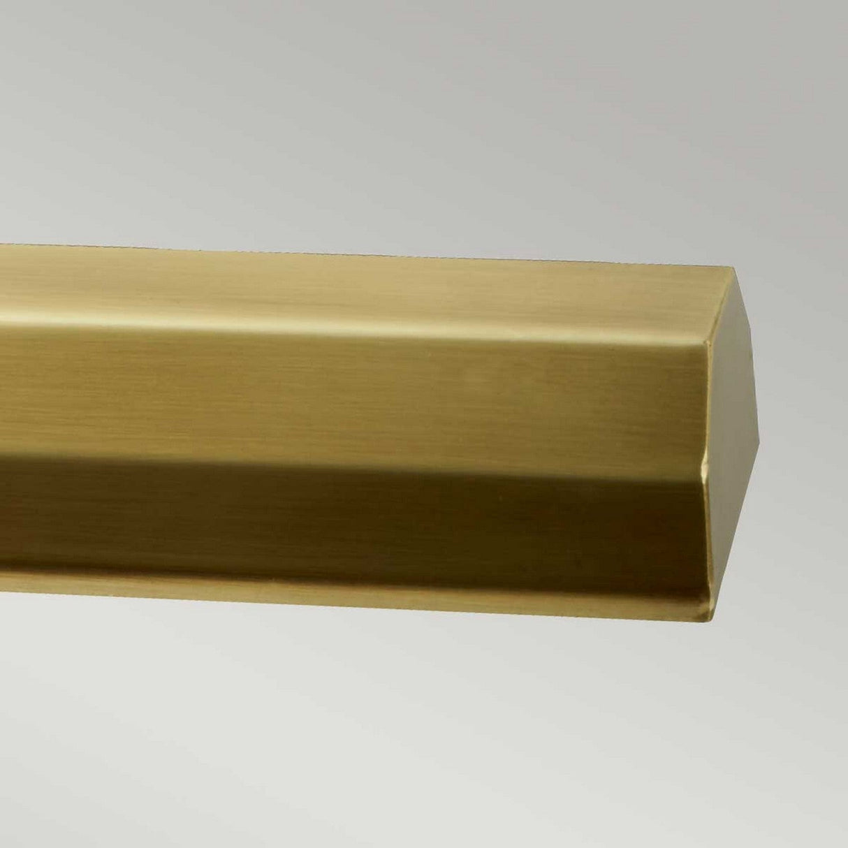 Close-up of a metal rod in aged brass featuring a rectangular cross-section, evocative of the Chawton Large Picture Light - Aged Brass, set against a plain gray background—perfect for enhancing directional lighting.