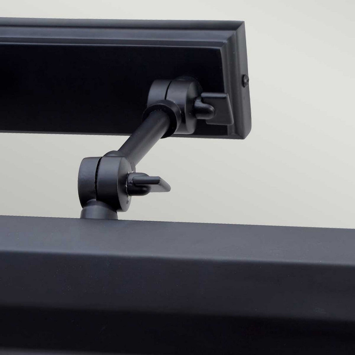 Close-up of a contemporary, adjustable black Chawton Large Picture Light with a sleek matte black finish. The spotlight highlights the arm and flexible knuckle joints, set against a light gray background.