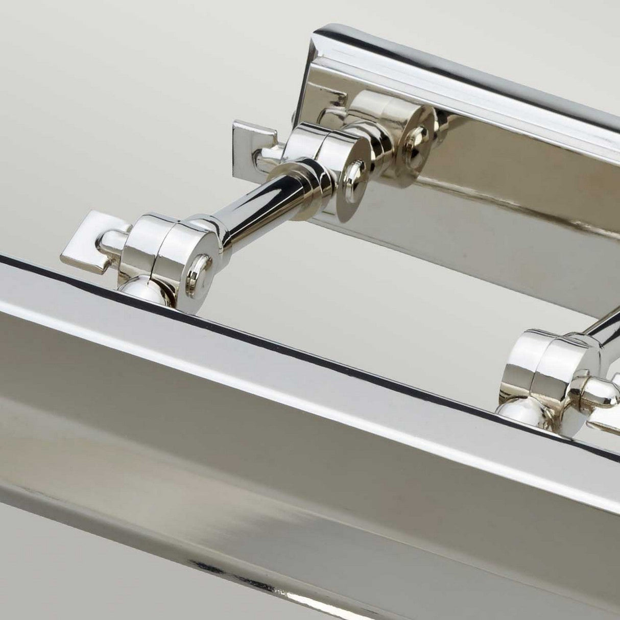 Close-up of the Chawton Large Picture Light in polished nickel, highlighting its intricate components and reflective surface. The neutral background enhances the shiny finish, emphasizing details reminiscent of adjustable knuckle joints.