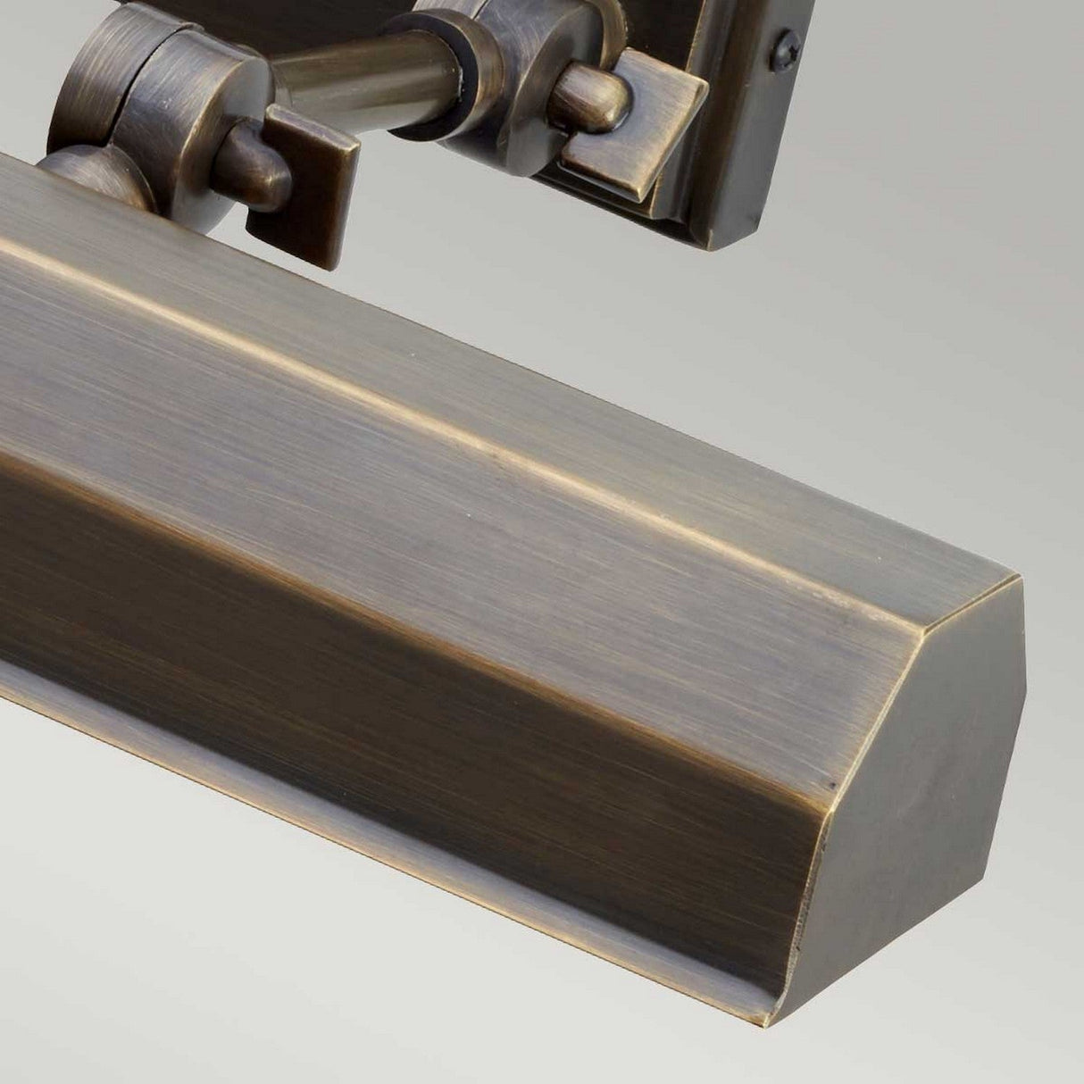 Close-up of an antique brass wall-mounted Chawton Medium Picture Light in Dark Bronze with a rectangular shade, ideal for artwork illumination. The fixture has an adjustable arm and is set against a light gray background.