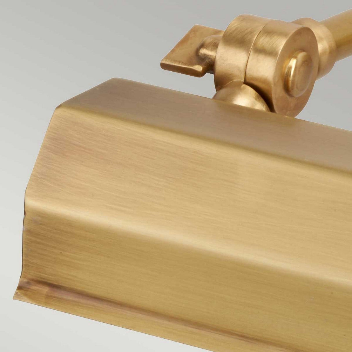 Close-up of the Chawton Small Picture Light in aged brass, highlighting its directional lighting with an angular design and a pivoting joint. The light features a polished finish, displayed against a neutral background.