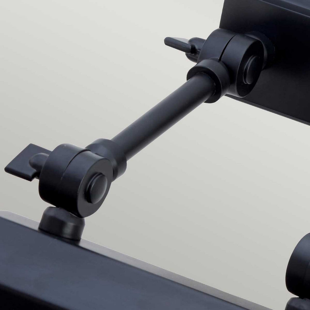 Close-up of a Chawton Small Picture Light in black, featuring sleek knuckle joints and mounted securely. The light arm is extended horizontally, blending seamlessly with modern décor and highlighting its functionality against a neutral background.