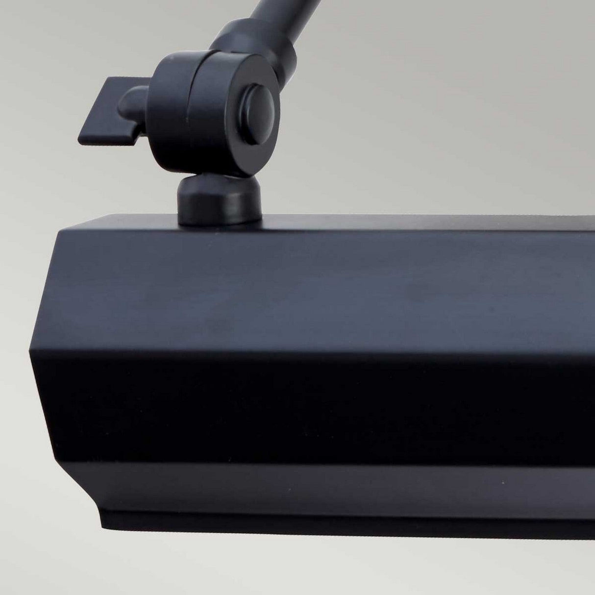 Close-up of the Chawton Small Picture Light in black, showcasing its adjustable knuckle joints against a gray background. The lamp includes a rectangular head and a pivot joint for directing light, ideal for modern décor.