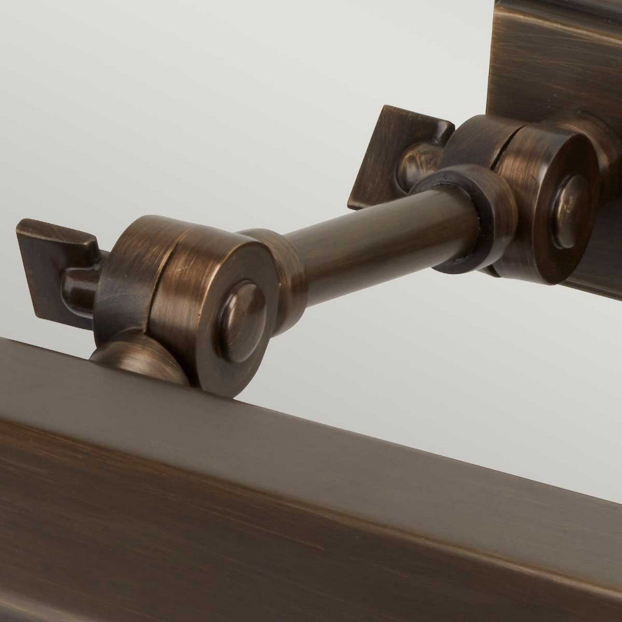 Close-up of a dark bronze-finished metal hinge system connecting two rectangular frames. The sophisticated modern design highlights adjustable knuckle joints with cylindrical pivot points and a matte texture, showcasing its robust construction and functional style inspired by the Chawton Small Picture Light - Dark Bronze.
