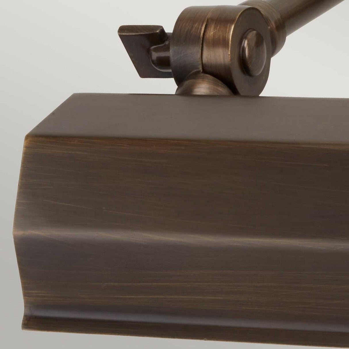 A close-up of the Chawton Small Picture Light in dark bronze showcases its angular design with adjustable knuckle joints at the top for precise positioning.