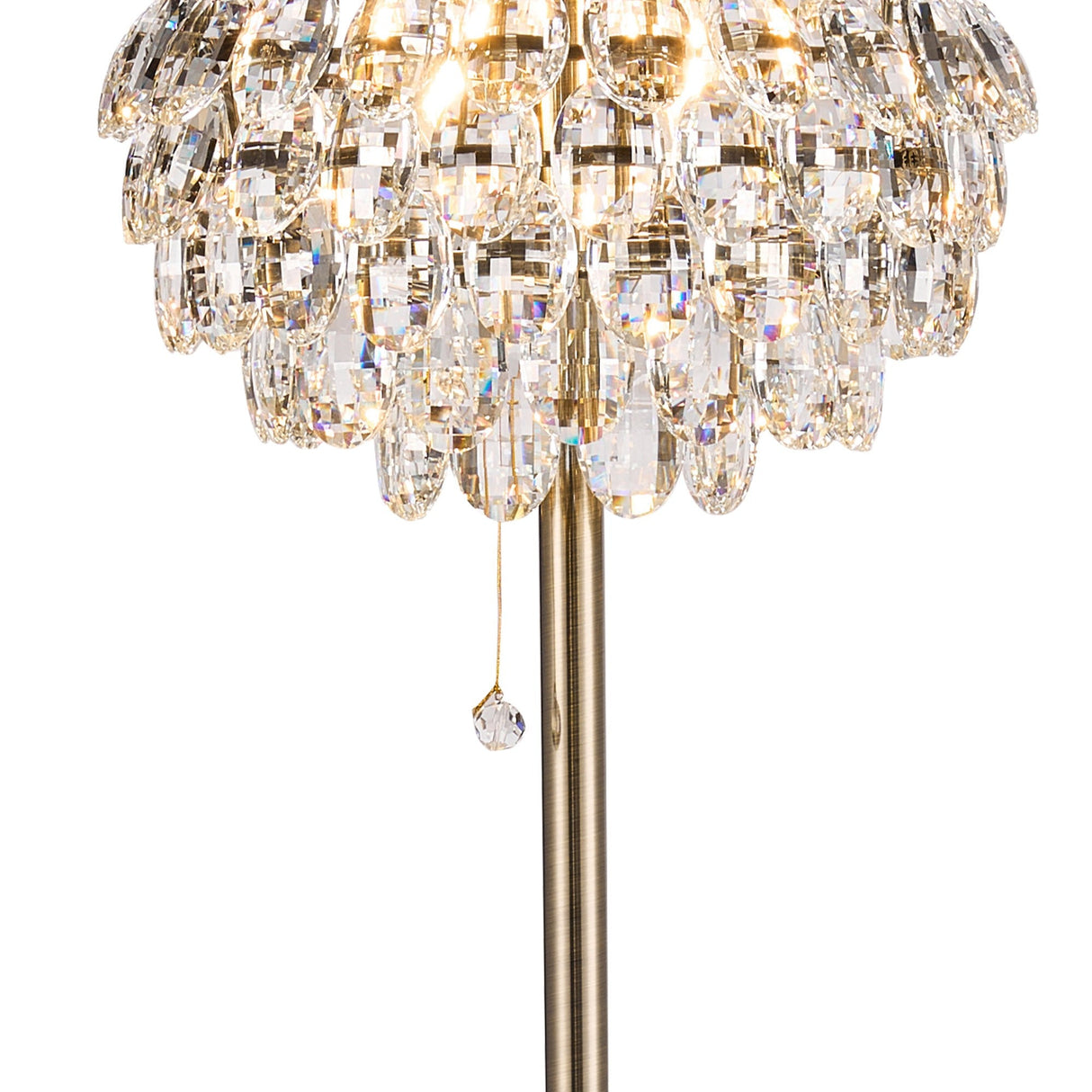 A close-up of the Coniston 3 Light Crystal Floor Lamp in antique brass, featuring multiple teardrop-shaped glass pieces, a hanging pull chain, and a gold metallic pole. When lit, it creates a sparkling effect.