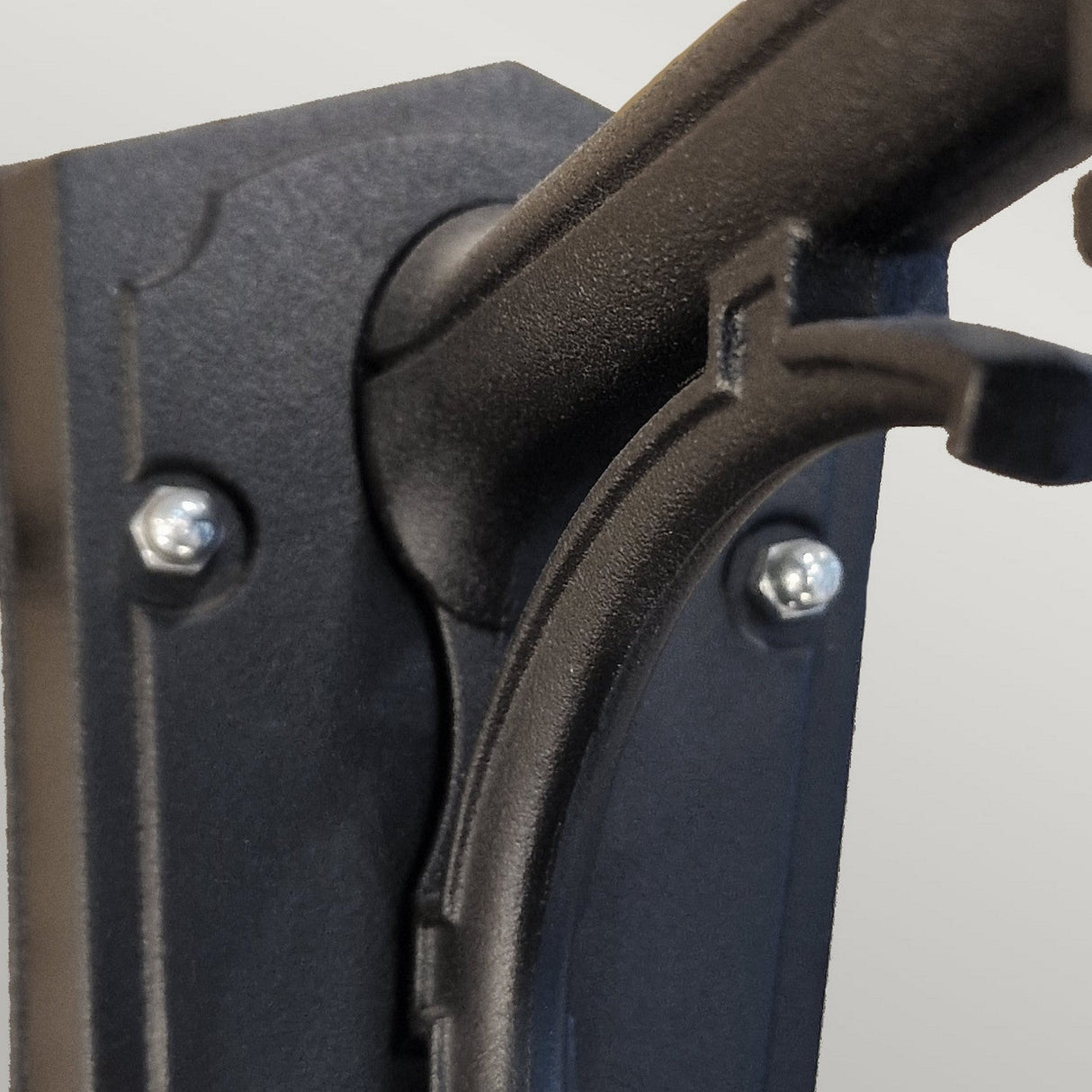 Close-up of the Chapel 1 Light Outdoor Up Wall Lantern - Black, featuring a black die-cast aluminium wall-mounted bracket with screws. This design securely holds the lantern and has a slightly curved open hook shape for easy placement and removal. The background is plain and neutral, making it an ideal choice for outdoor lighting.