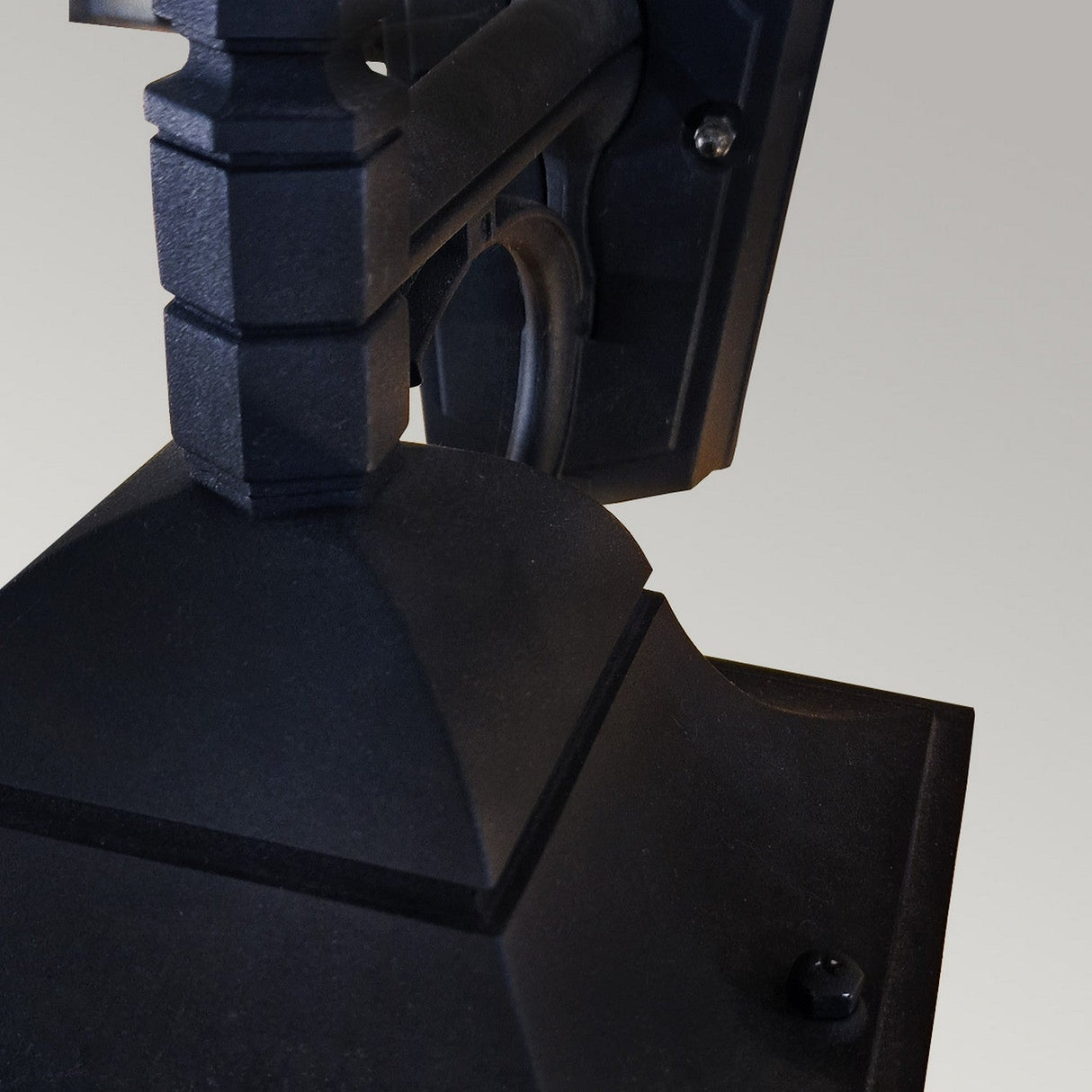 Close-up of the Chapel 1 Light Outdoor Down Wall Lantern in a black finish, showcasing its textured surface and geometric design. The lantern is mounted on a light-colored wall, featuring a rectangular base with decorative elements and an IP44 rating for enhanced durability.