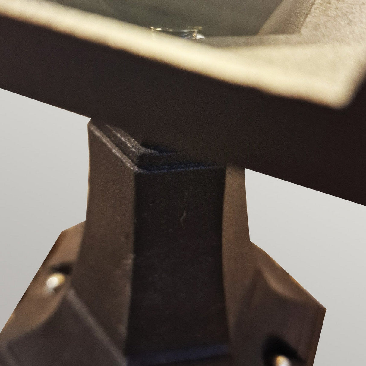 Close-up of the Chapel 1 Light Outdoor Mini Pedestal Lantern in black, featuring an angular design with sharp lines and a textured die-cast aluminum surface. Set against a plain light grey background, it may offer an IP44 rating for enhanced durability.