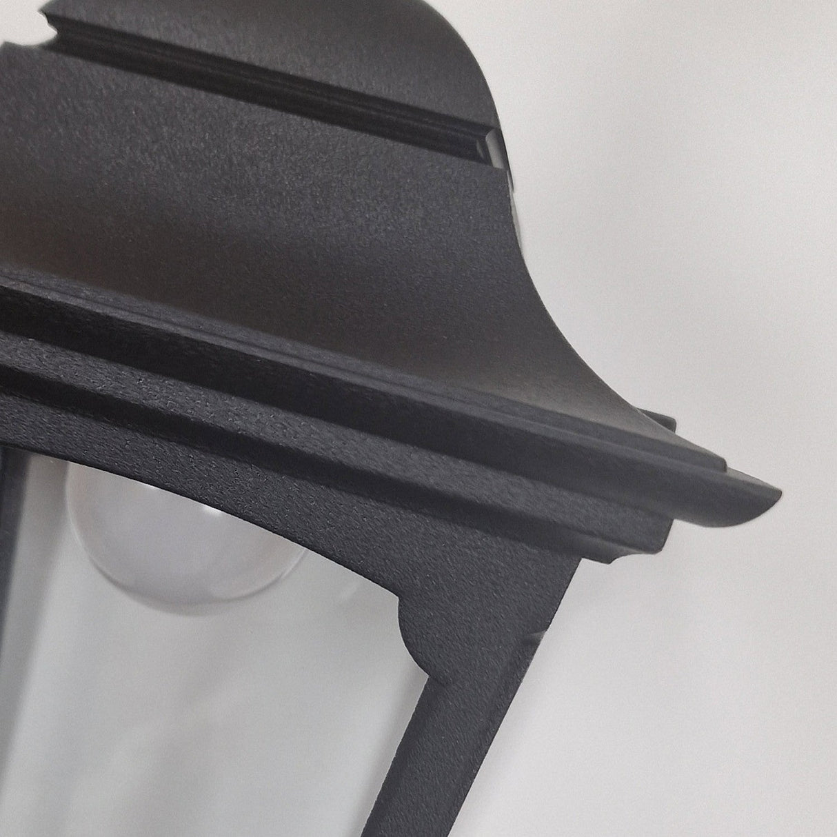 Close-up of the Chapel 1 Light Outdoor Mini Chain Pendant in black, featuring a lantern-style design crafted from die-cast aluminum with a transparent glass enclosure. The matte finish of this outdoor lighting piece elegantly contrasts against a plain, light background.