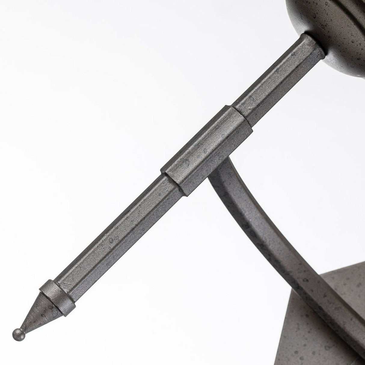 Here's a possible rewrite using the provided product data:
"Close-up of the Crown 2 Light Wall Light in graphite finish, showcasing its timeless design. The piece resembles a futuristic object with a long pointed rod connected to a spherical element, enhancing its textured surface and geometric elegance.