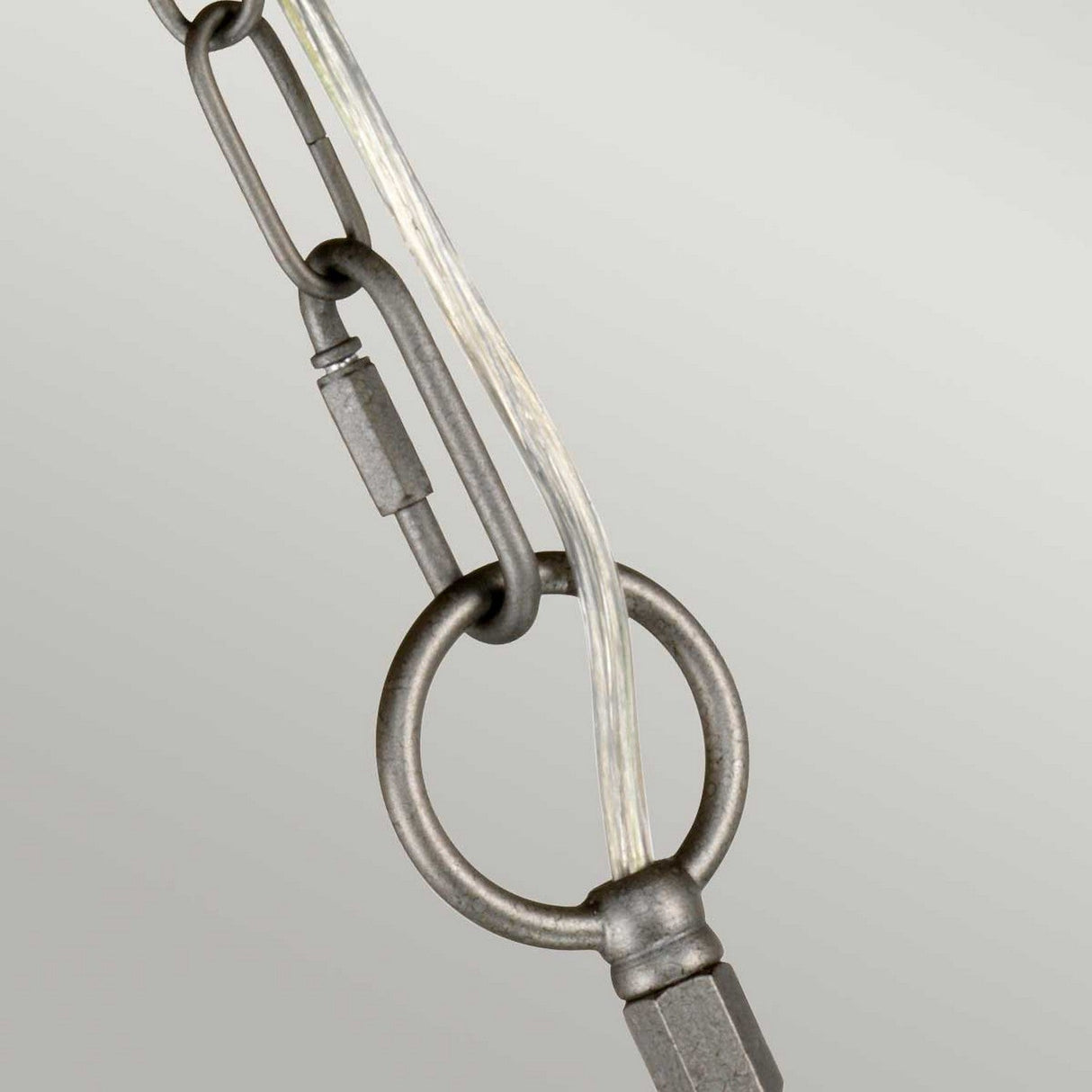 Close-up of the Crown 3 Light Chandelier - Graphite, featuring a metal chain with a parallel cord elegantly threaded through a round loop, highlighting modern craftsmanship. The light gray, graphite-toned background accentuates the chain and loop design.