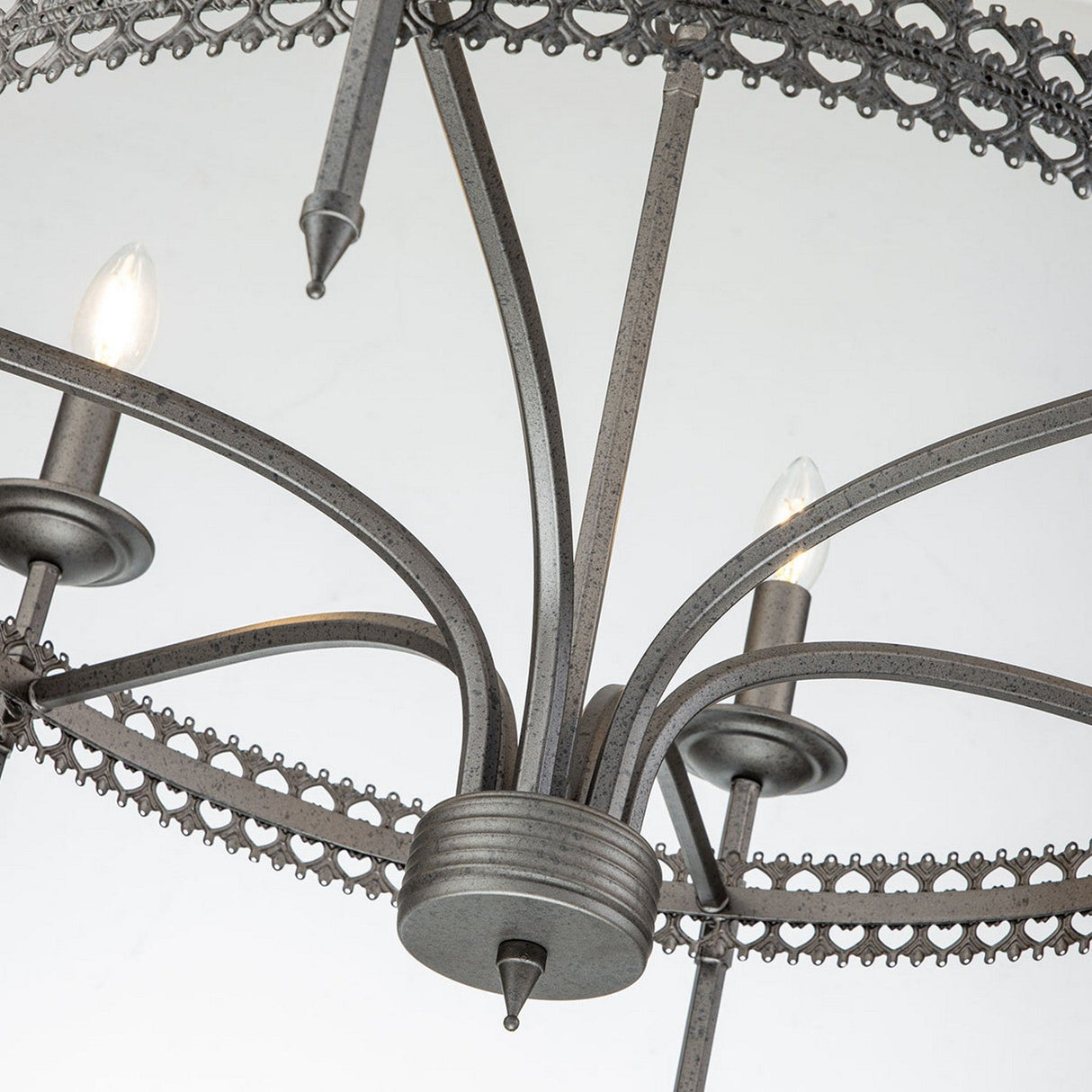 Close-up view of the Crown 6 Light Chandelier in Graphite, showcasing intricate detailing with multiple curved arms and candle-like light bulbs. This graphite chandelier features decorative edging that exudes regal elegance.