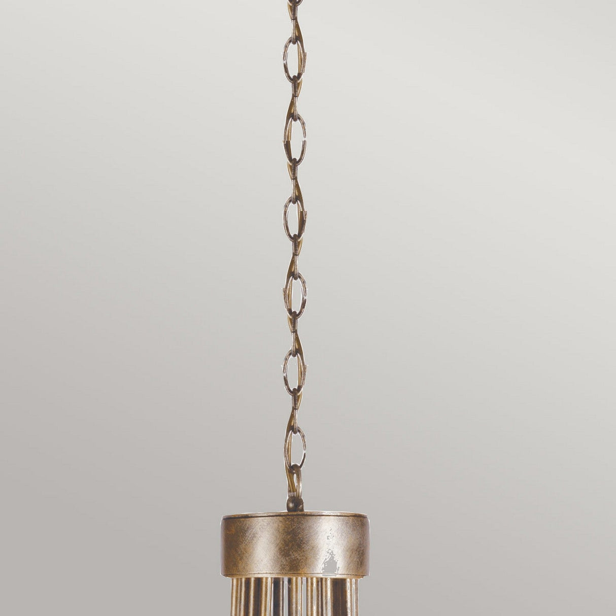 The Christina 18 Light Chandelier, featuring a silver and gold patina, boasts a brass-colored design that hangs elegantly from a decorative chain. Its cylindrical base with vertical ridges is displayed beautifully against a neutral background.