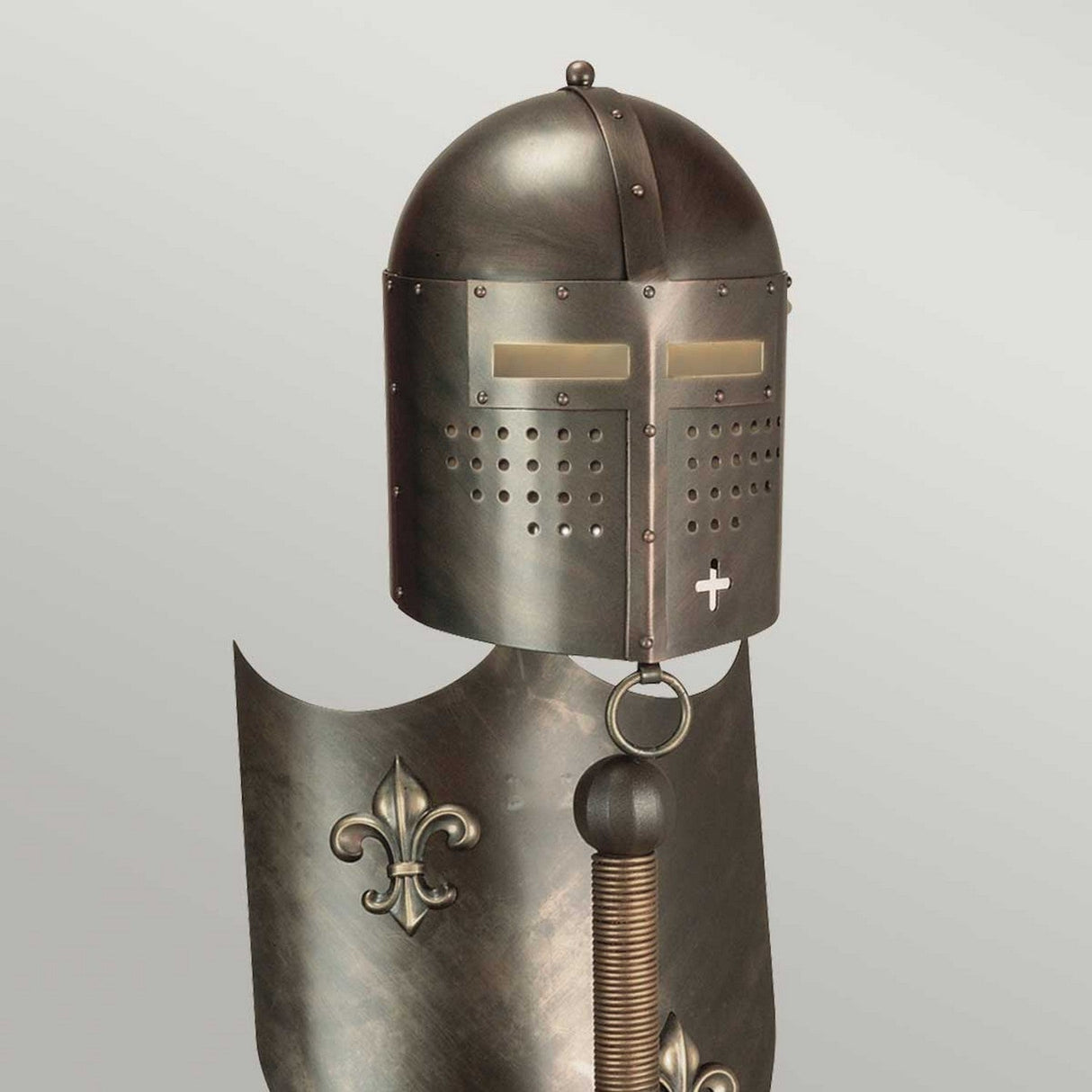 A medieval-style suit of armor, with its exquisite craftsmanship, highlights a helmet adorned with a cross-like visor and a decorative fleur-de-lis crest on the chest. This stunning piece stands gracefully against a neutral background, evoking the appearance of the Crusader Table Lamp in burnished bronze.