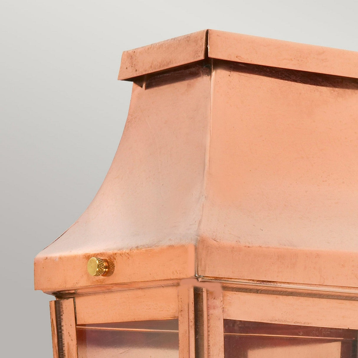 Close-up of the top section of the Chelsea Outdoor 1 Light Small Half Lantern - Copper, showcasing its handcrafted, smooth curved design. It features a small round brass knob on one side and a glass panel beneath, making this IP44 rated lighting piece stand out against a simple light gray background.