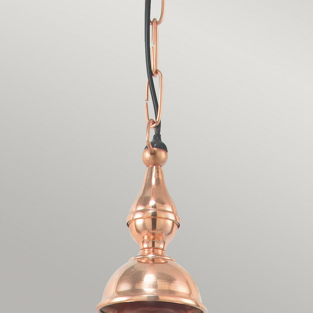 A detailed look at the Chelsea Outdoor 1 Light Chain Pendant in copper, featuring a black power cord and chain. This pendant light fixture showcases a polished, reflective surface with an intricate design set against a neutral gray background, ideal for outdoor lighting needs.