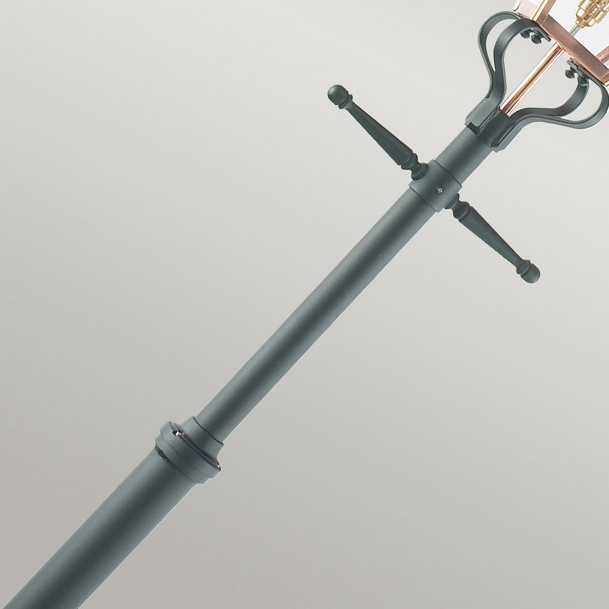 Close-up of the Chelsea 1 Light Grande Lamp Post, showcasing its dark-colored, industrial-style base with a classic design. It features a sleek pole with two horizontal handles and a metal framework at the top, set against a plain background.