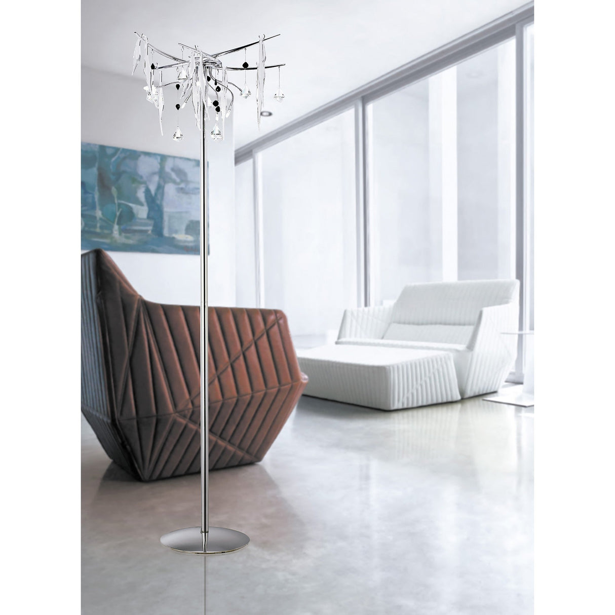 A modern living room with large windows, a white sofa, an angular brown chair, and the Cygnet 6 Light Glass & Crystal Floor Lamp in chrome—a statement piece adorned with hanging crystals and ornaments.