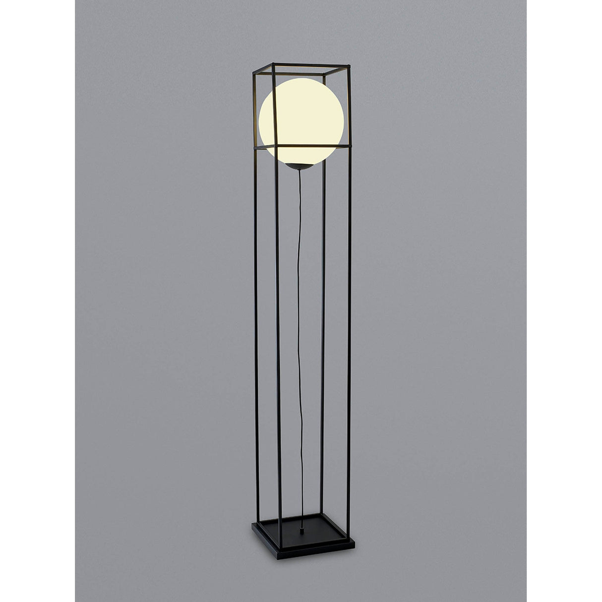 The Desigual Large 1 Light Floor Lamp in matt black showcases contemporary minimalism with a glowing spherical bulb inside an open metal frame, standing on a square base against a plain gray background.