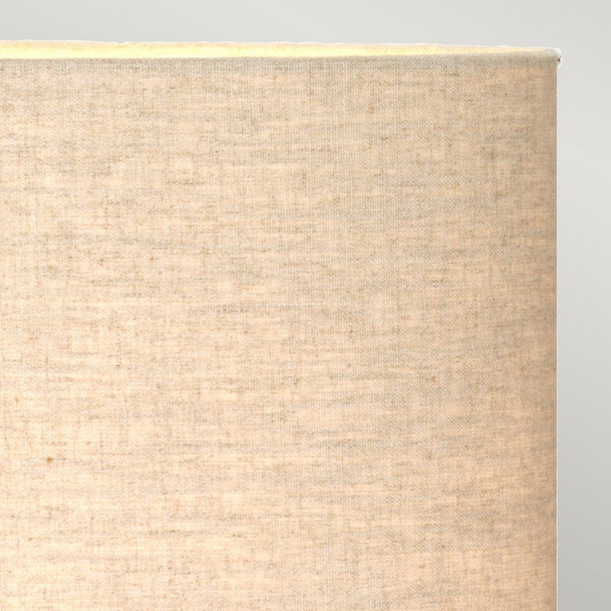 Close-up of a beige fabric texture, possibly part of an Angus-2 Table Lamp With Oval Shade in Bronze Patina or upholstered item, against a light gray background. The fabric has a subtle weave pattern, creating a soft, neutral appearance.