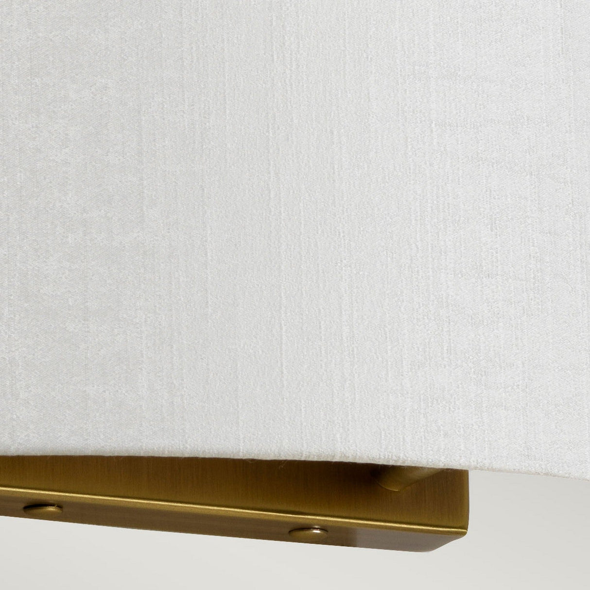 Close-up of the Cooper Large Curved Wall Light in aged brass, featuring an elegant design with a white fabric shade. The texture of the fabric combined with the metallic sheen of the base exudes vintage charm while maintaining a luxurious and modern appearance.