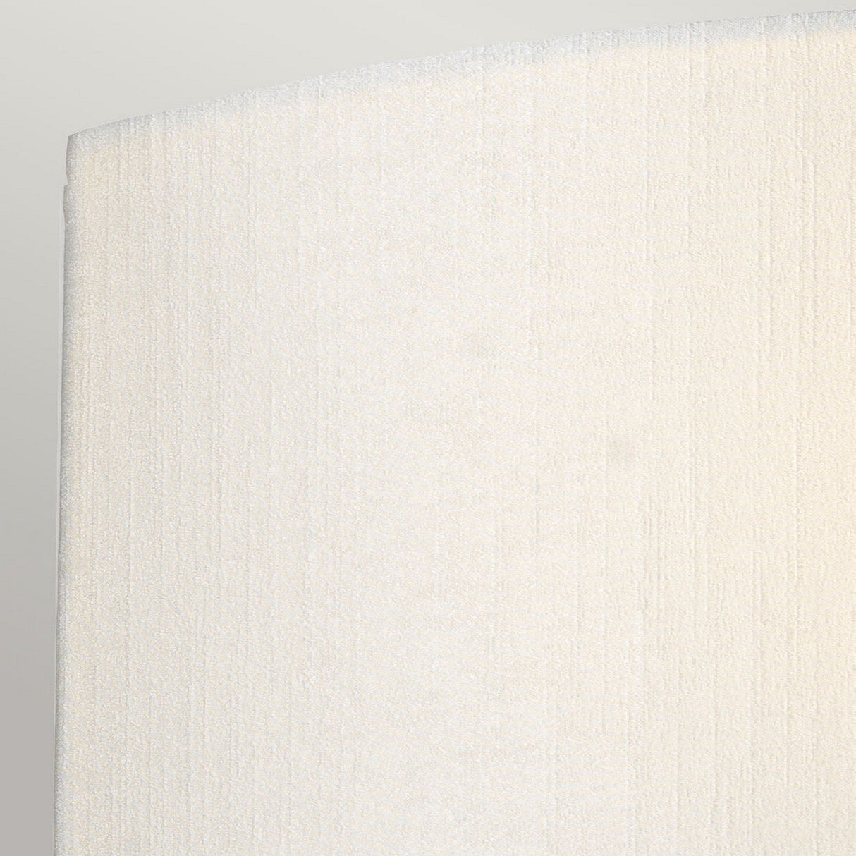 Close-up of a textured, off-white surface with a subtle vertical pattern that exudes vintage charm. The smooth, curved edge on the left, reminiscent of aged brass from the Cooper Large Curved Wall Light, is set against a light gray background.
