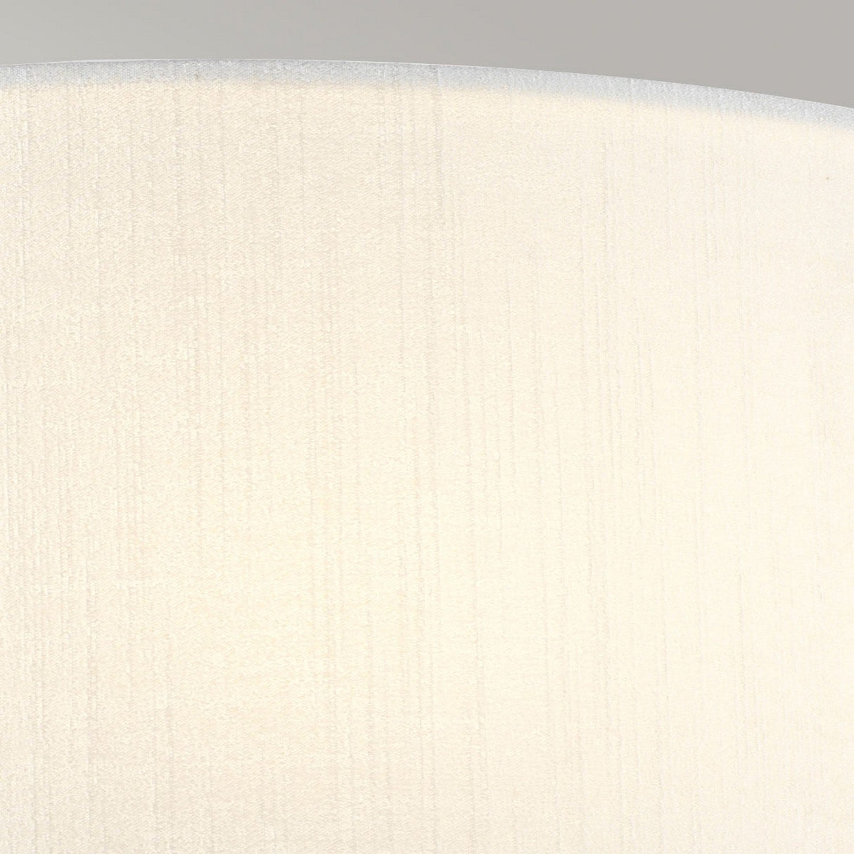The Cooper Large Curved Wall Light in Polished Chrome features a textured, light beige fabric with subtle vertical lines that resemble a faux silk shade, giving the appearance of being illuminated from within. This fabric texture enhances depth and creates a gentle gradient effect, providing warm and soft ambient lighting.