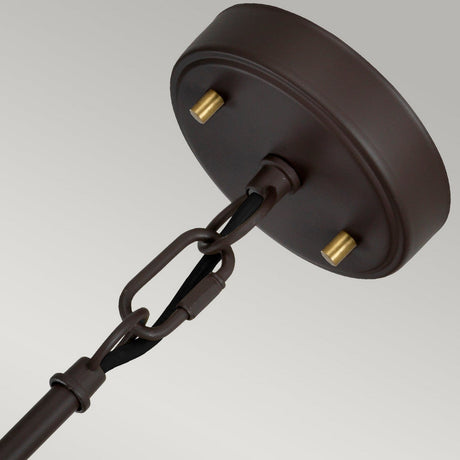 A close-up of a Corona 2 Light Pendant / Semi-Flush - Bronze Dark Brown featuring two brass bolts. The fixture is suspended by a black cord connected through chain links. Its sleek, circular base displays a matte finish, all set against a light gray background.