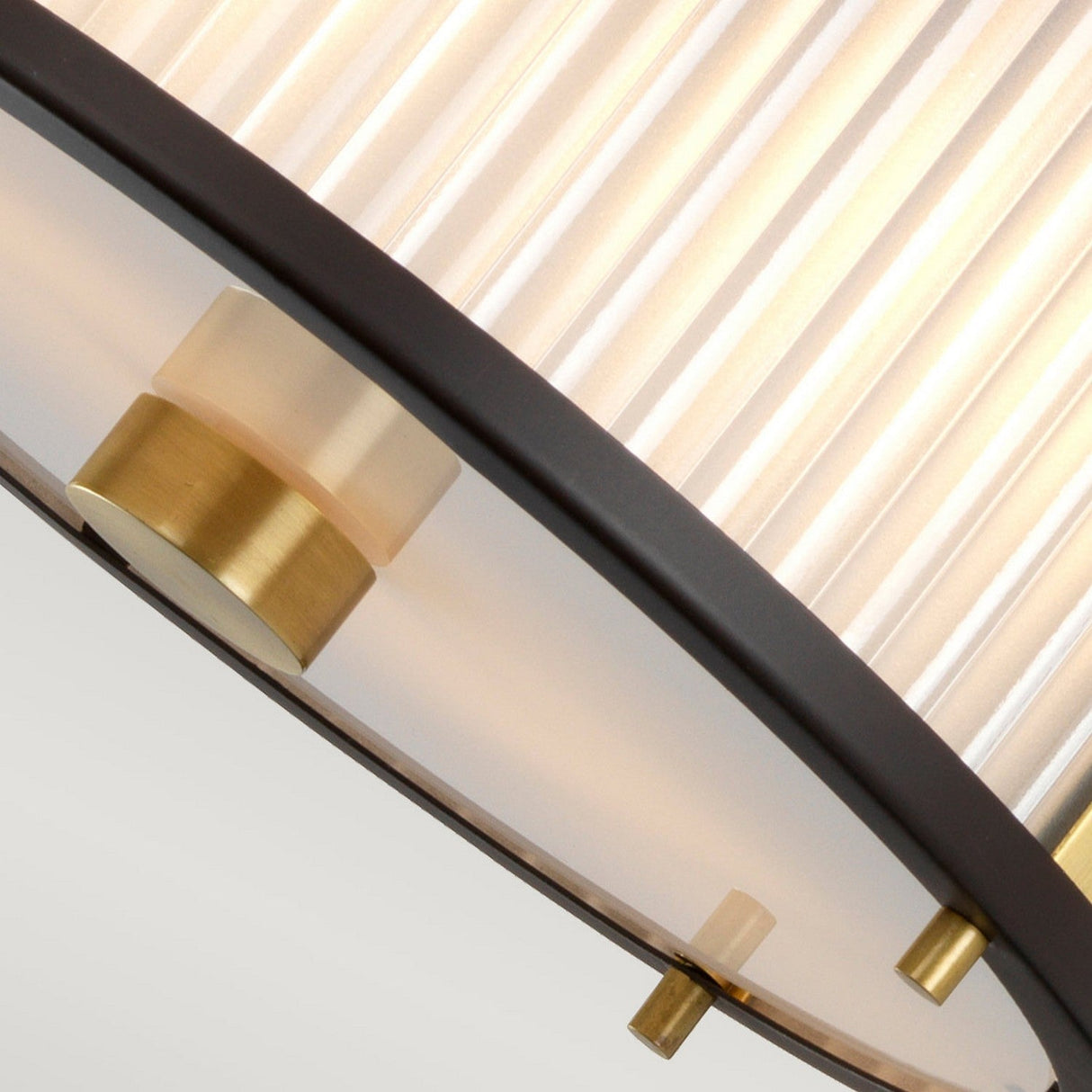 A close-up of a modern semi-flush light fixture showcases a ribbed, translucent shade that radiates with a warm glow. The design is enhanced by metallic accents in bronze and dark brown, offering a contemporary flair similar to the stylish Corona 2 Light Pendant / Semi-Flush - Bronze Dark Brown.