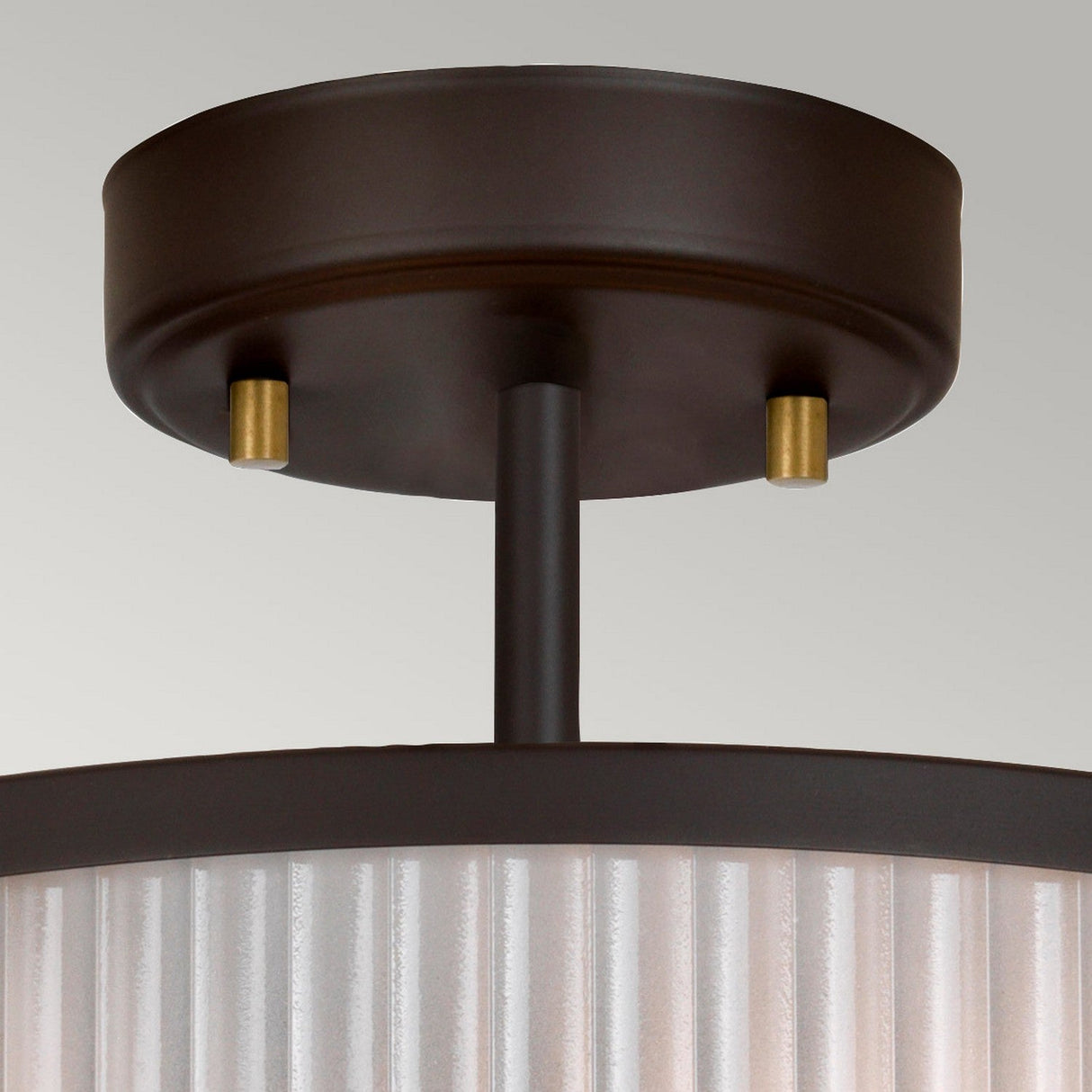 A close-up of the Corona 2 Light Pendant / Semi-Flush in Bronze Dark Brown, featuring a metal base and ribbed glass or plastic shade. This semi-flush fixture is mounted on a round, dark bronze base, with a short stem suspending the pendant, seamlessly blending with the neutral background.