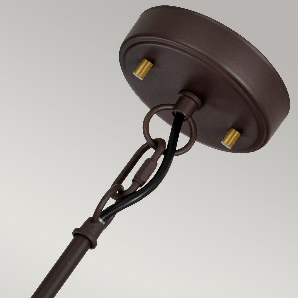 The product "Corona 3 Light Pendant / Semi-Flush - Bronze Dark Brown" features a close-up view of its bronze dark brown ceiling light fixture with a round base, highlighting the luxurious black and gold accents. The metal rod gracefully loops from the base, exemplifying a semi-flush design. The fixture contrasts beautifully against the simple, light-colored background.