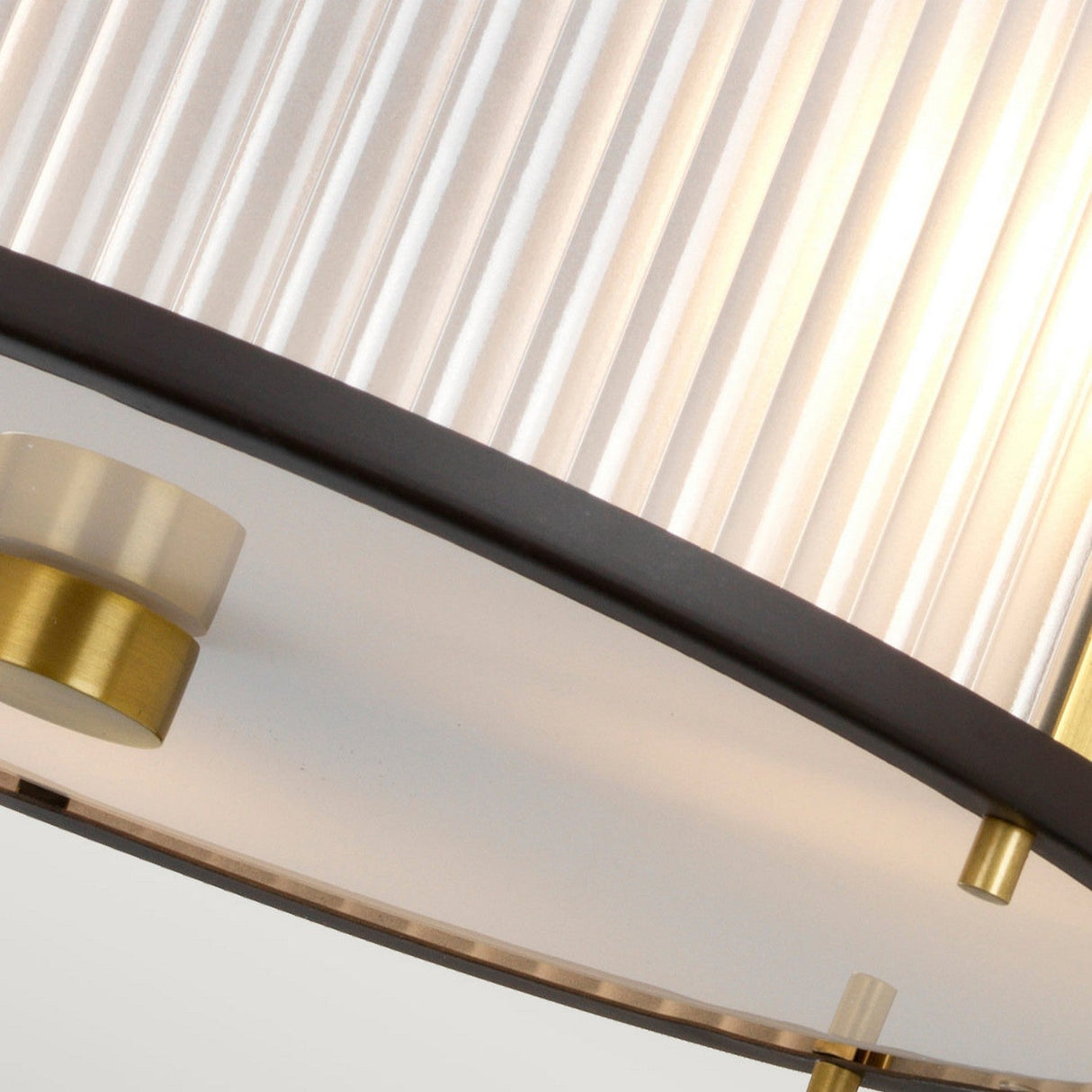 A close-up of the Corona 3 Light Pendant, featuring a circular gold frame and ribbed white lampshade. This design highlights contemporary elements with its combination of semi-flush black and gold accents, enhanced by bronze dark brown finishes.