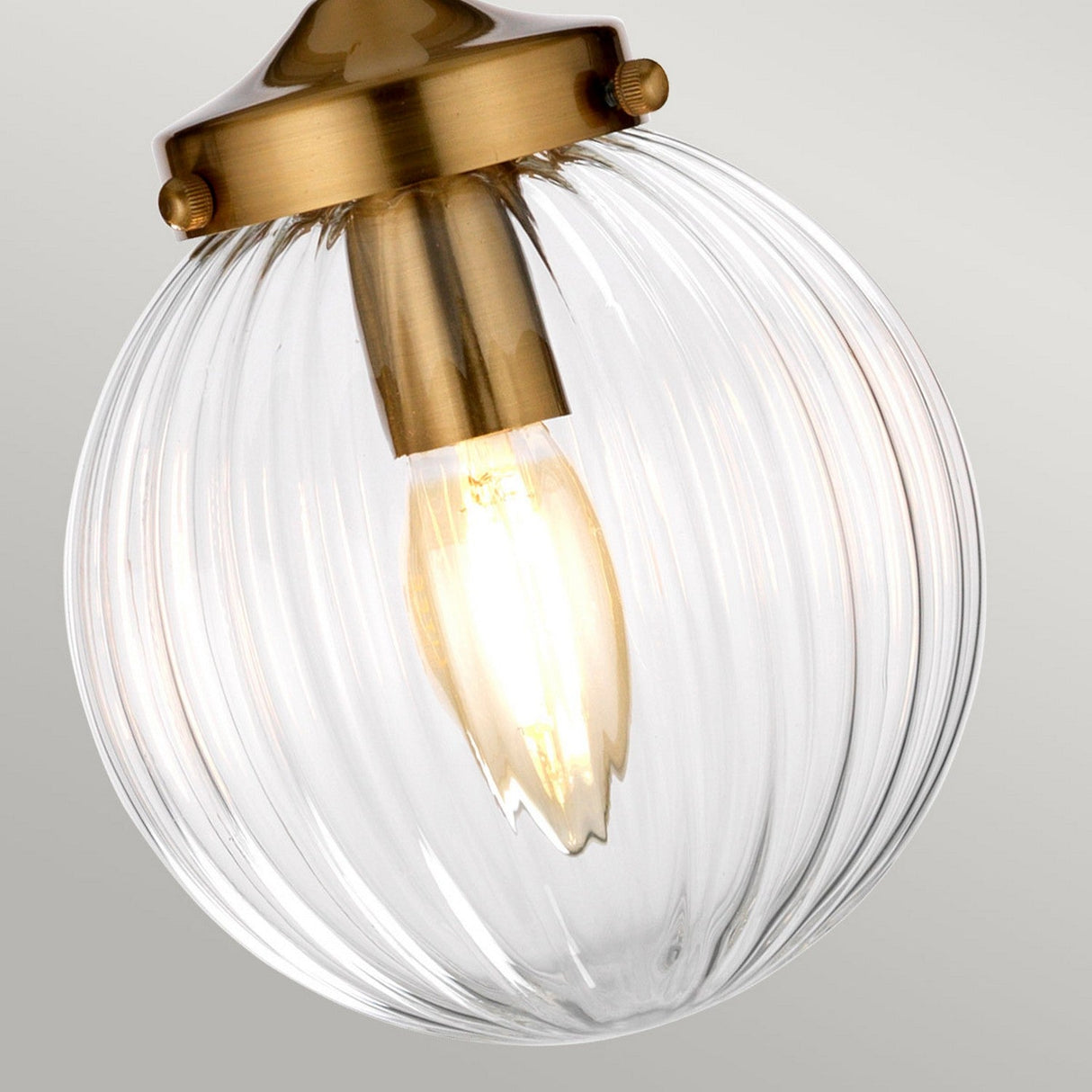 The Cosmos 1 Light Pendant, with its cream painted finish and aged brass accents, boasts a vintage-style bulb encased in a hand-blown glass shade featuring grooved texture. This design casts a warm, retro-style glow that enhances the elegance of any space.