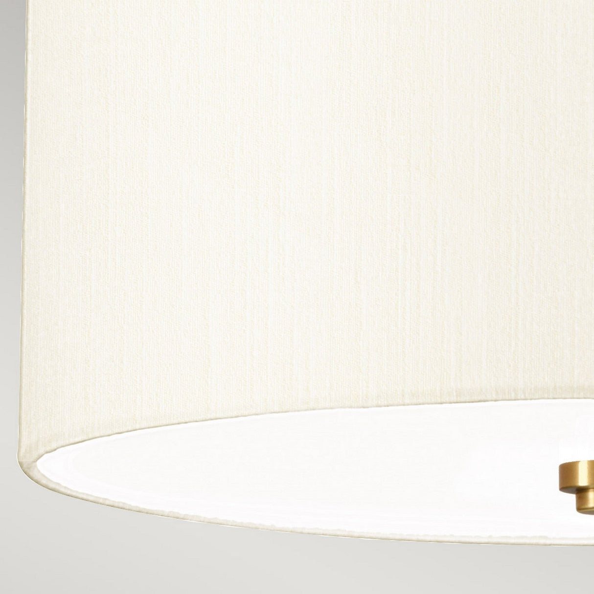 Close-up of the Fletcher 14" Flush pendant light fixture in aged brass, showcasing a sleek ivory shade made of cream-colored faux silk with a subtle texture. The lower edge features a white diffuser underneath, providing an elegant and minimalist appearance against a light background.