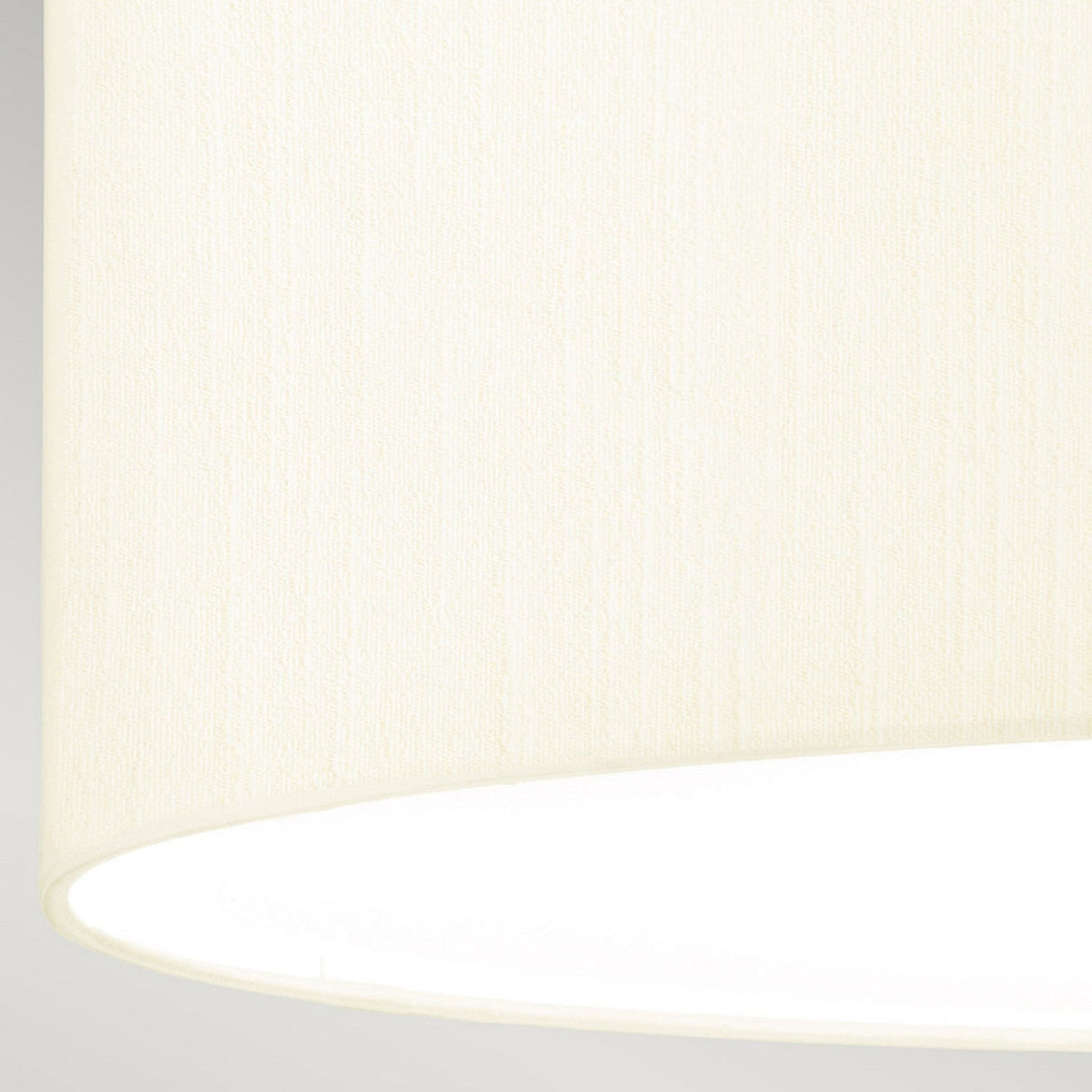 A close-up of the ivory shade made from faux silk, showcasing its smooth texture against a neutral background. The light is turned on, casting a warm and subtle glow over the lower part of the Fletcher 18" Flush Ceiling Fixture with an aged brass finish.