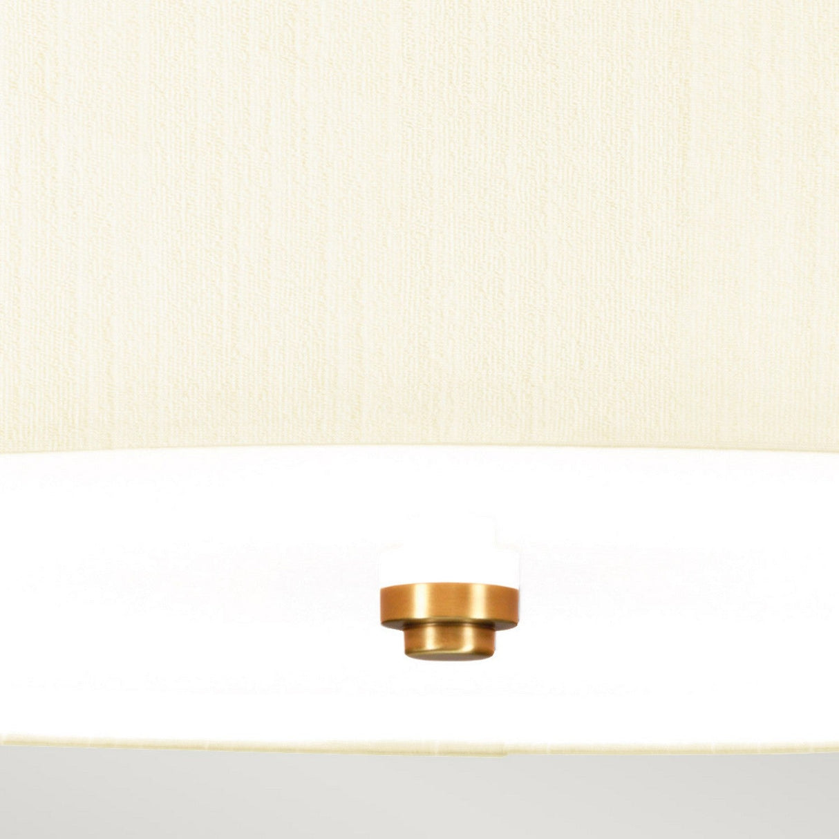 A close-up of the Fletcher 22" Flush with its aged brass cylindrical base and ivory shade contrasts beautifully against a light beige textured background, showcasing its minimalist design and metallic sheen.