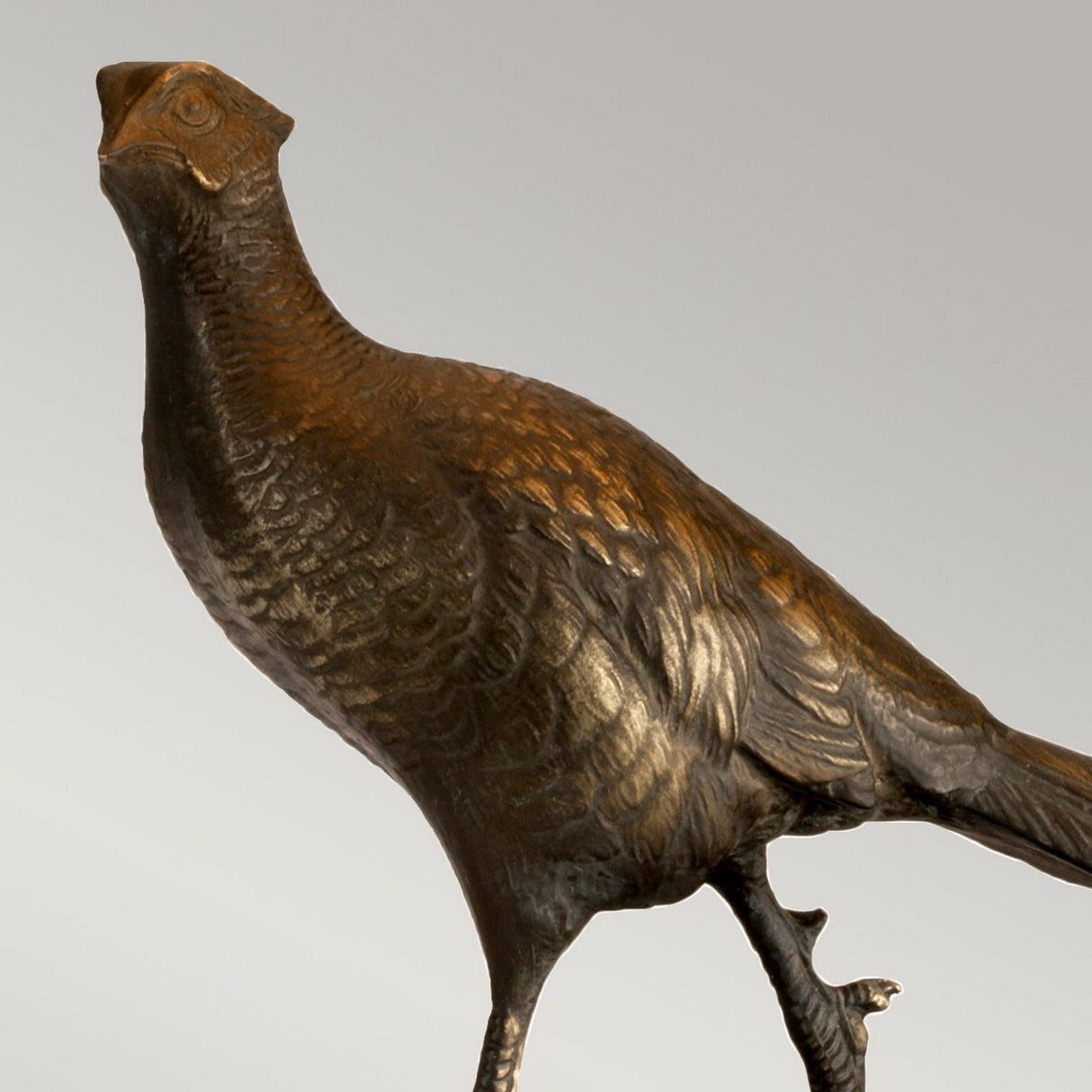 Halkirk Table Lamp With Rectangle Shade features a detailed bronze patina and lifelike depiction, reminiscent of a pheasant statuette with finely crafted elements. The design, set against a simple backdrop, offers an upward-looking and elegant appearance.