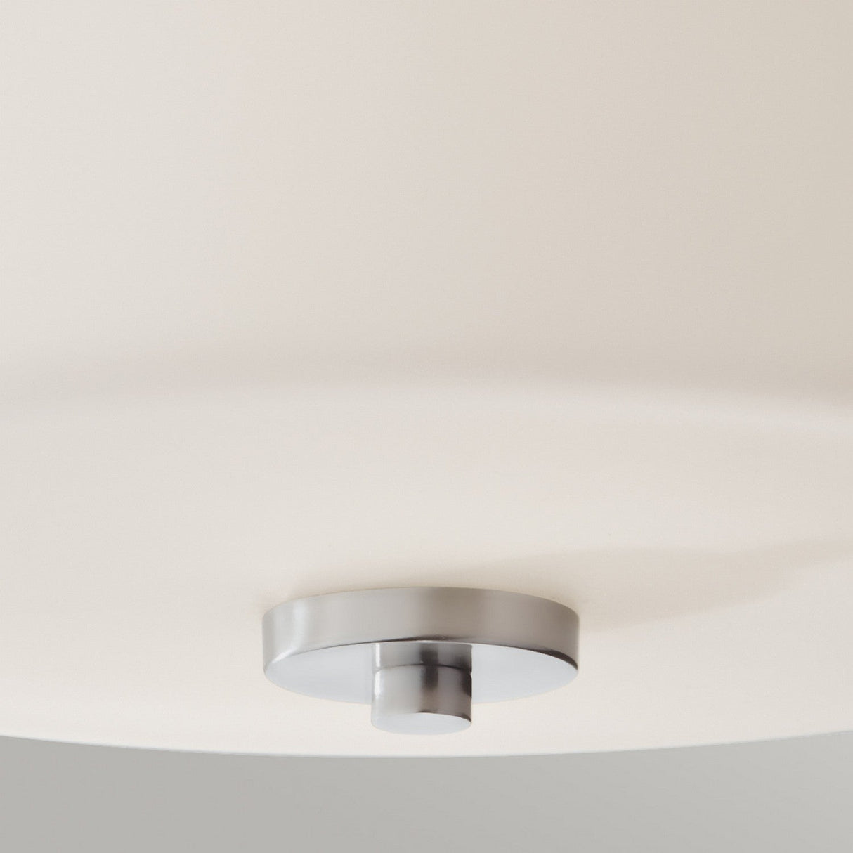 Close-up of the Kincaid 2 Light Flush with a polished chrome, round base attached to a white ceiling. This modern ceiling light fixture features a minimalist design that casts a subtle shadow, offering a clean and contemporary appearance.