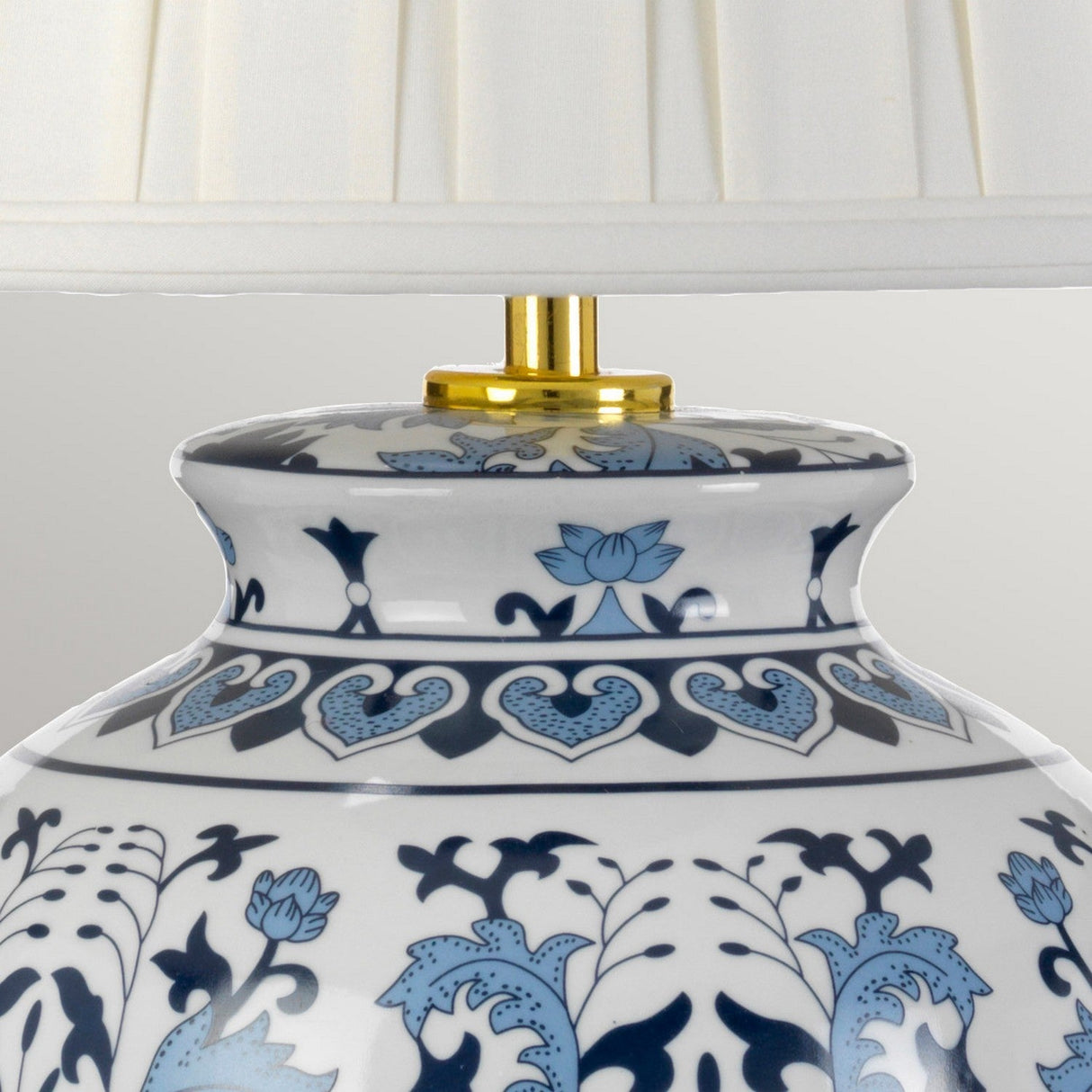 Close-up of the Linyi Table Lamp with a tall empire shade, showcasing its elegant ceramic base adorned with intricate blue and white floral and heart patterns. The lamp is complemented by a brass neck, enhancing its sophisticated charm.