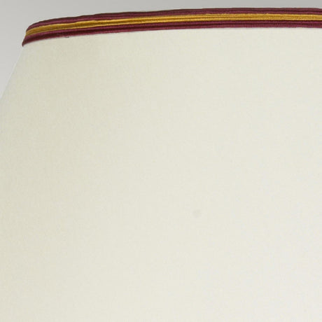 Close-up of a Tall Empire shade with a smooth cream surface and a trim featuring brown, orange, and yellow stripes along the top edge, perfectly complementing the Majin Table Lamp With Tall Empire Shade - Oxblood.