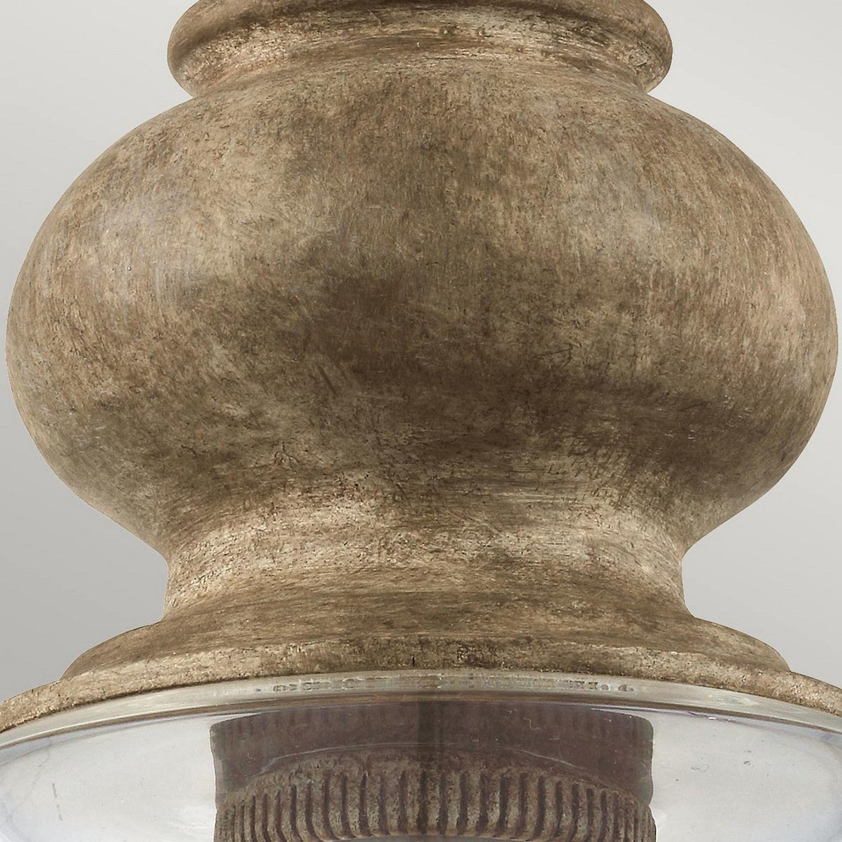 Close-up of the Matrimonio 1 Light Pendant, featuring a warm driftwood and dark weathered zinc finish, showcasing an antique rustic allure. The design includes a textured, bulbous shape with a clear glass rim perfectly visible against a neutral background.