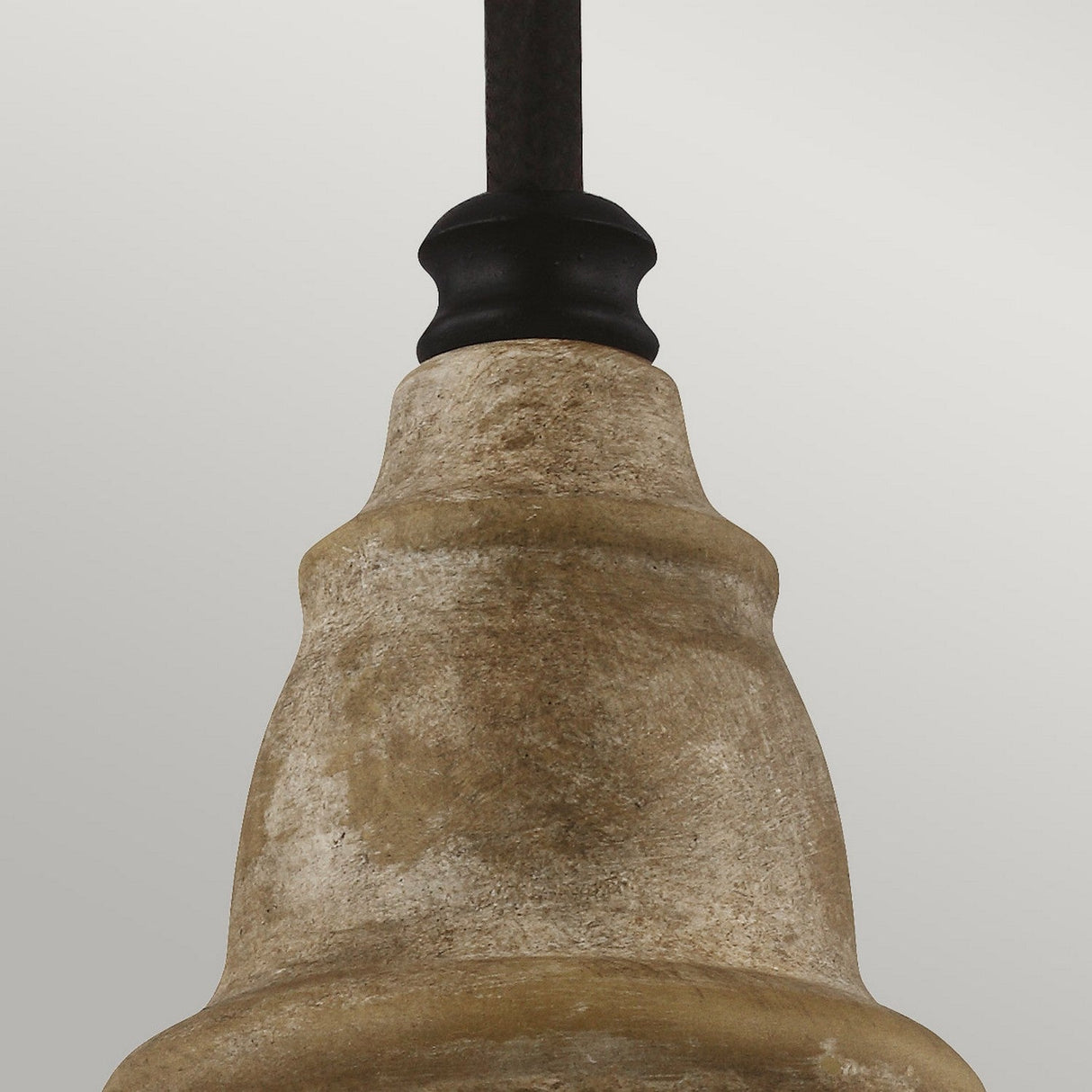 Close-up of the Matrimonio 1 Light Mini Pendant, crafted in a textured stone or clay design, featuring a black metal support at the top. The rustic lighting elements and driftwood finish offer a natural appearance set against a light gray background.